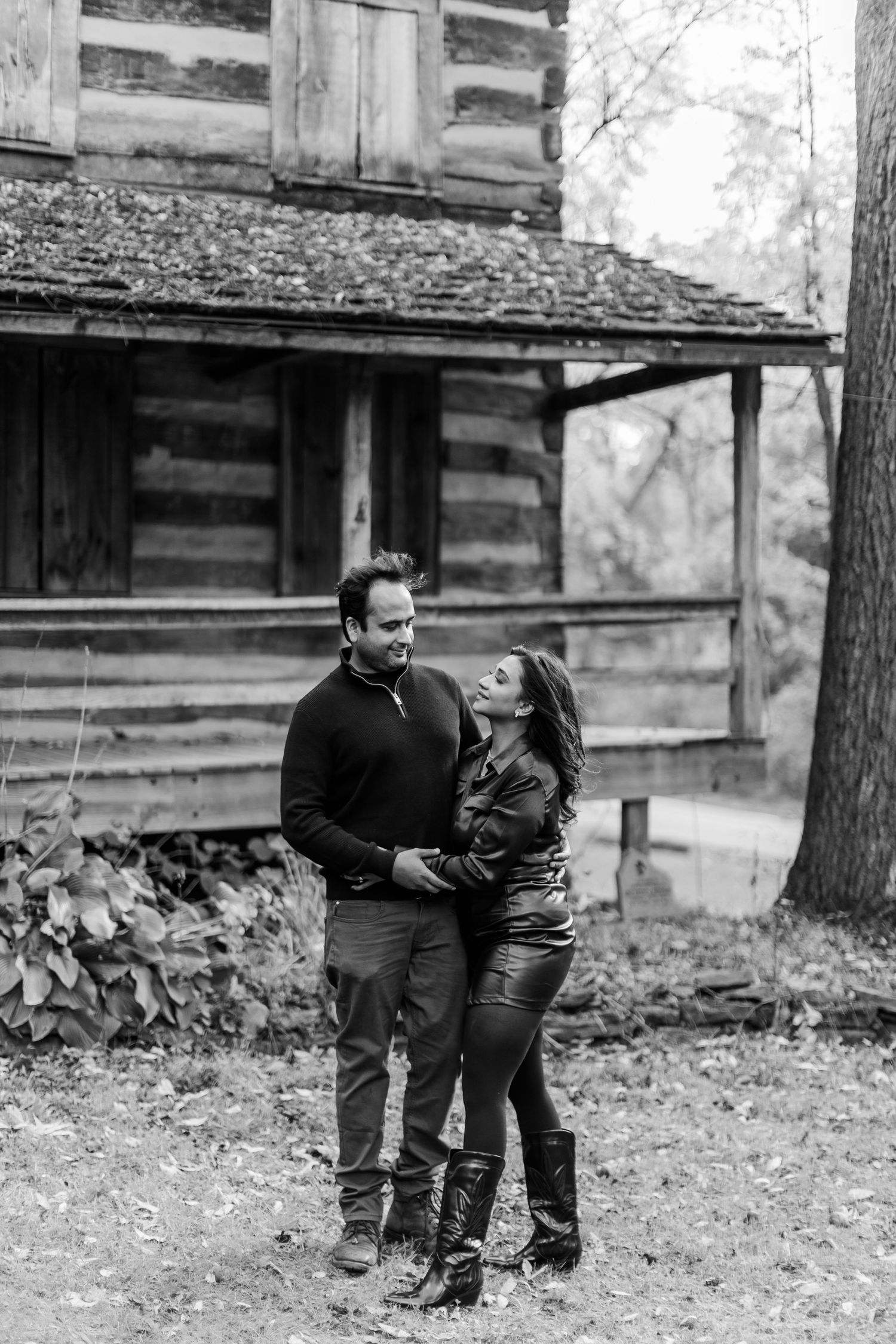 Couple embracing in front of a rustic log cabin during autumn.
