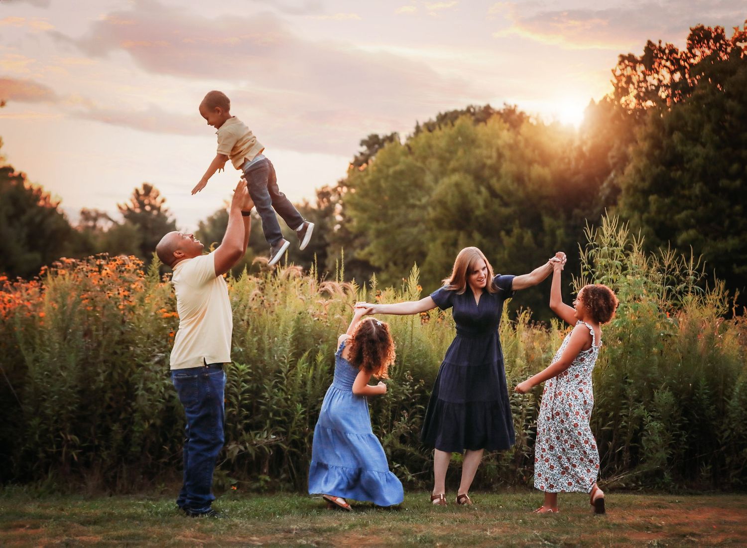 Playful family lifestyle session in a field during golden hour.