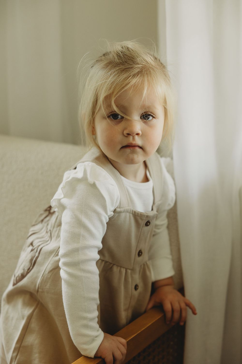 A series of close-up portraits showing a small child in white and beige overalls against a light background.