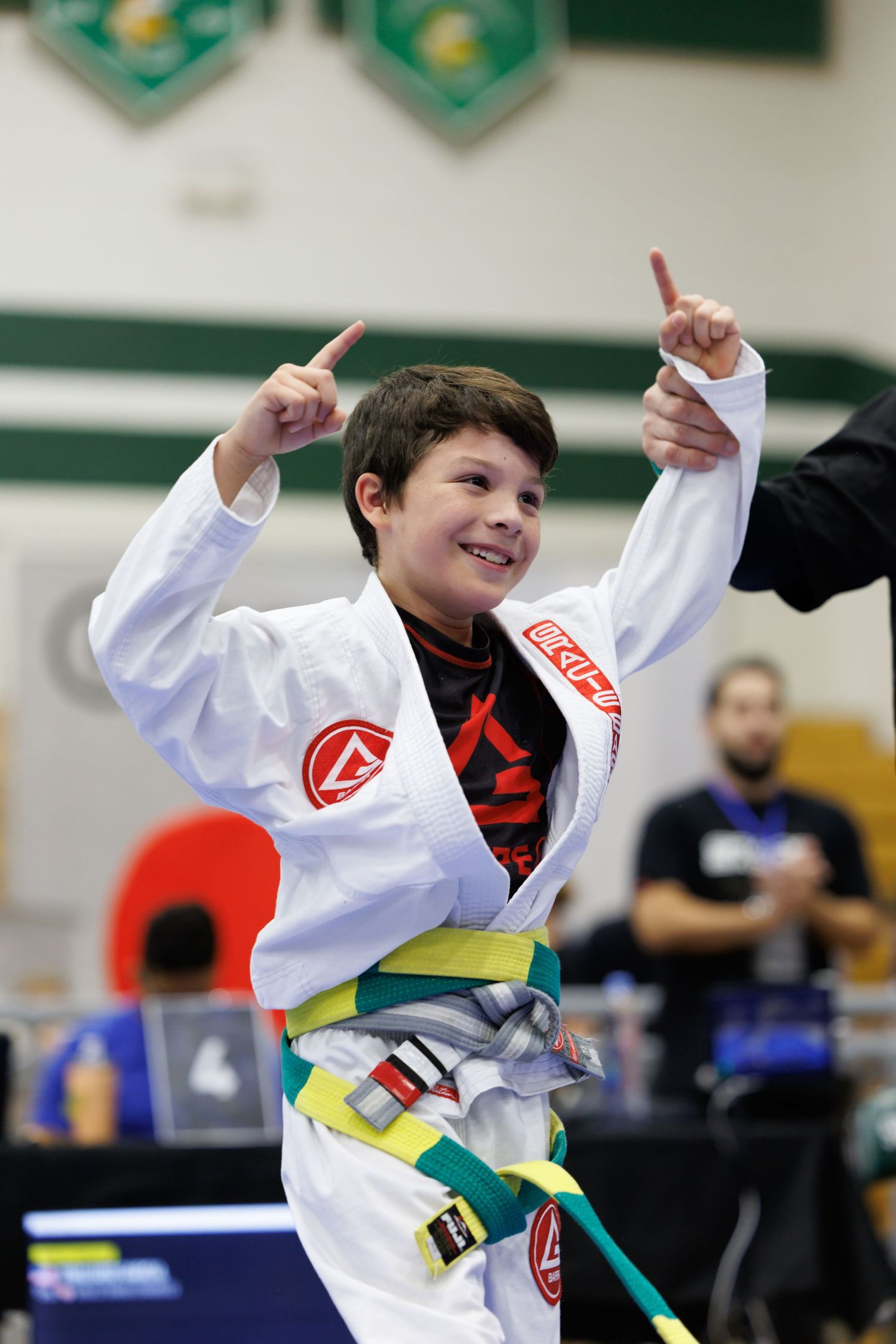 Young martial arts student in white gi performing high kicks during training.