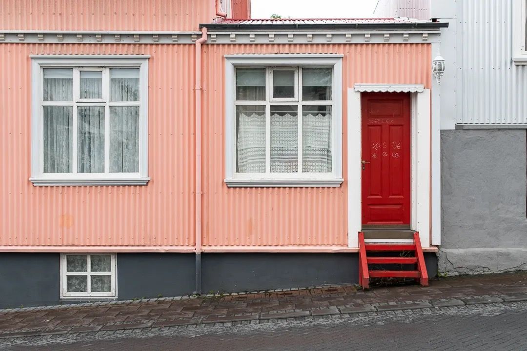 Peach-coloured house façade with white trim and a red front door.