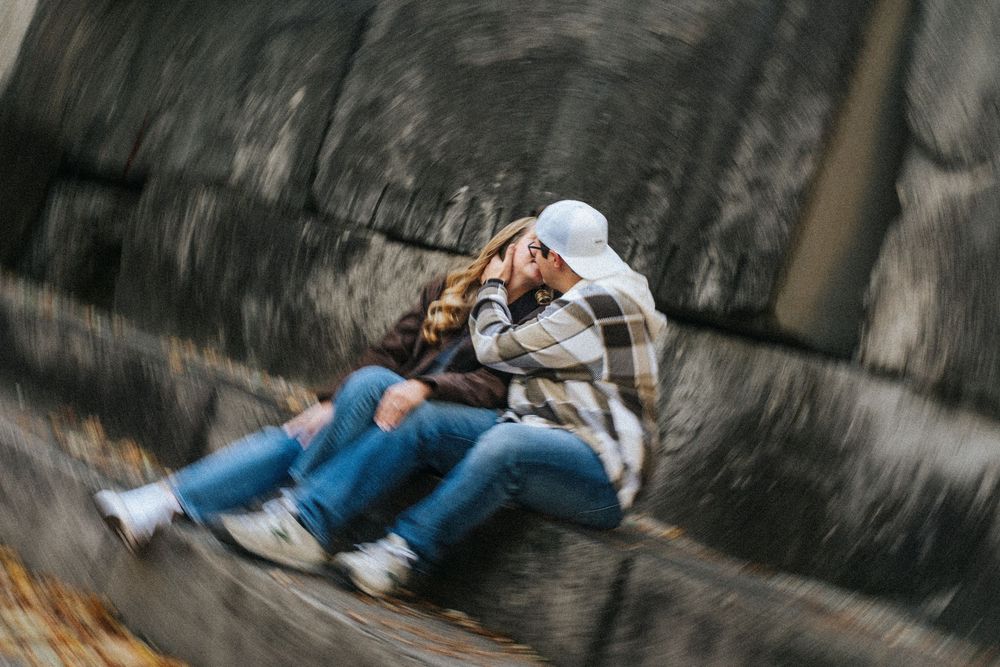 Motion blur photo of someone in jeans and white hoodie swinging on a rope swing in an outdoor setting.