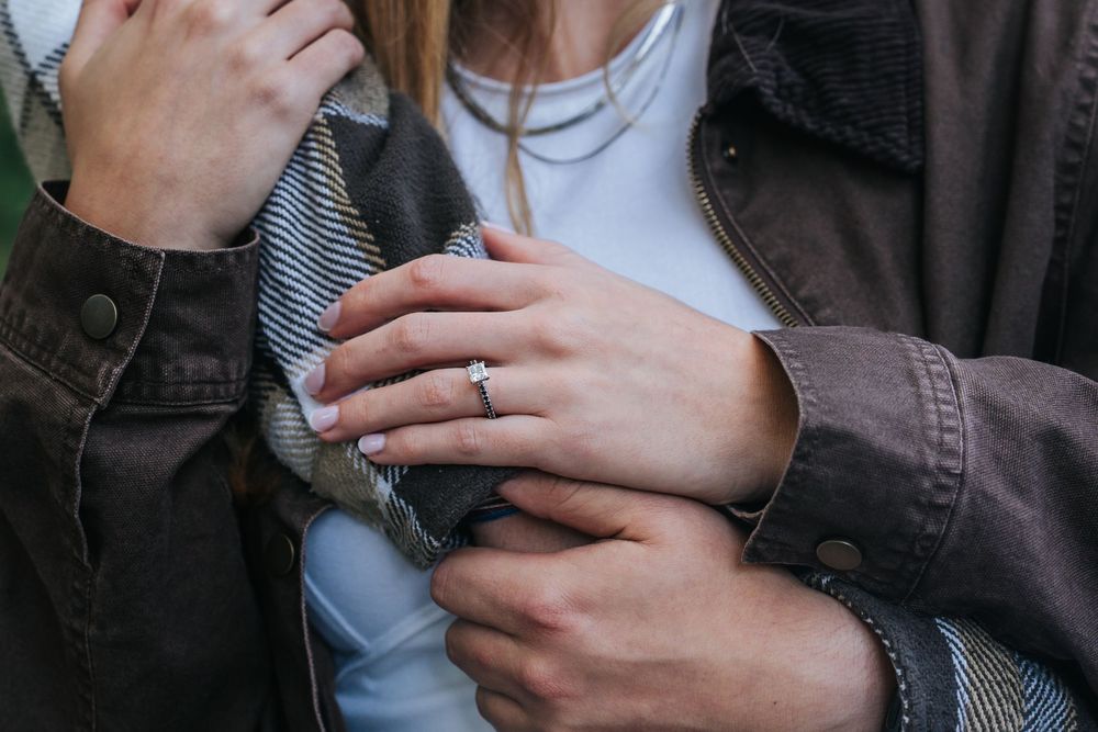 Close-up view of hands holding a hot beverage in a dark ceramic mug against a blurred background.