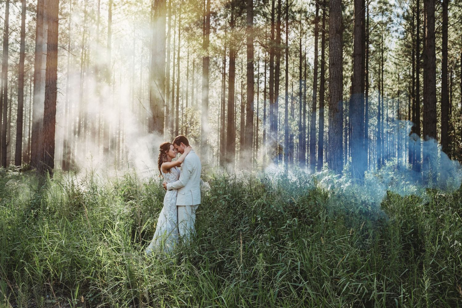 A couple embracing in a misty forest with blue smoke effects.