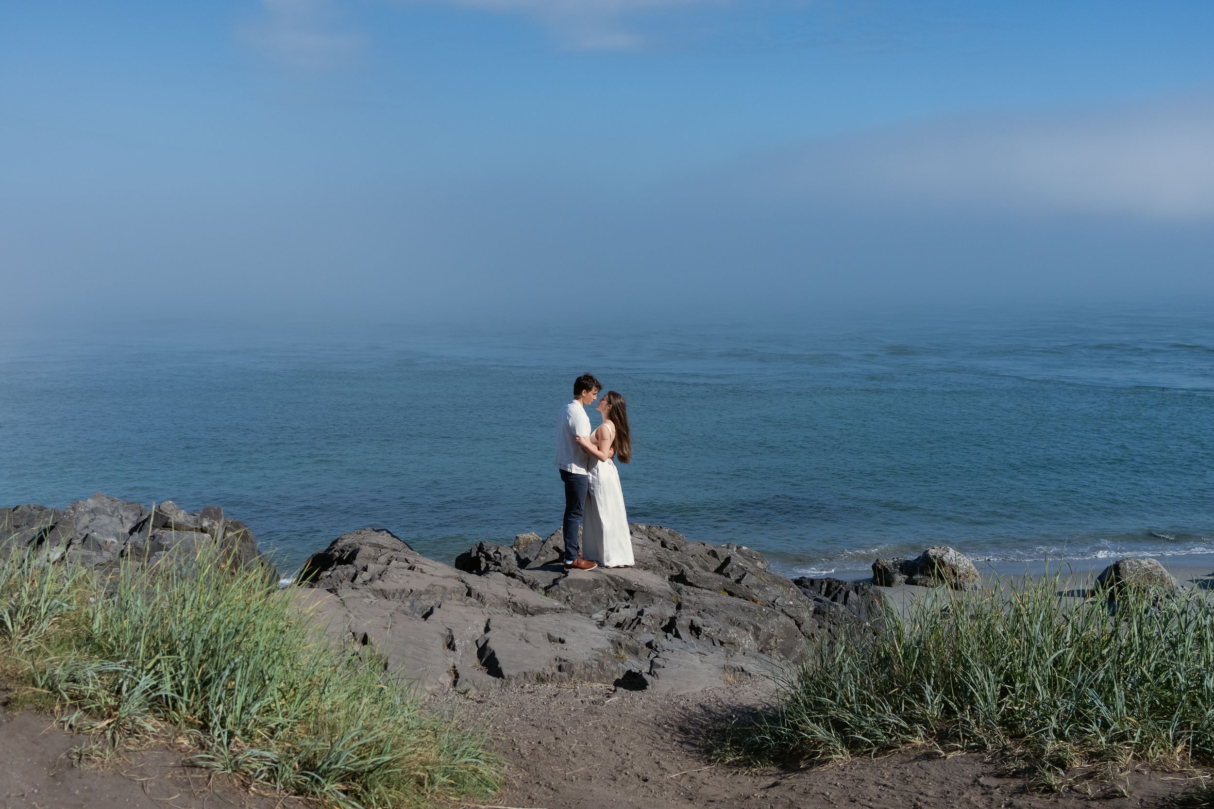 Panoramic view of a rocky coastline with blue ocean waters and a couple, captured by Savvy Photography - Seattle Wedding Photographer
