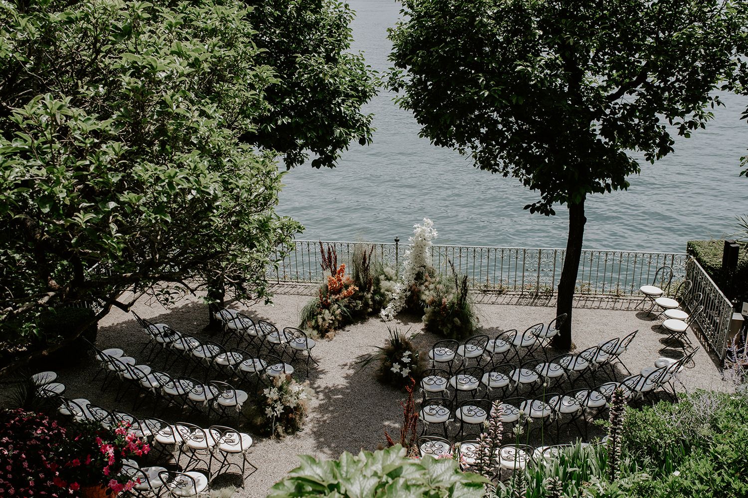 Outdoor wedding ceremony setup with white chairs overlooking a scenic lake and mountains.