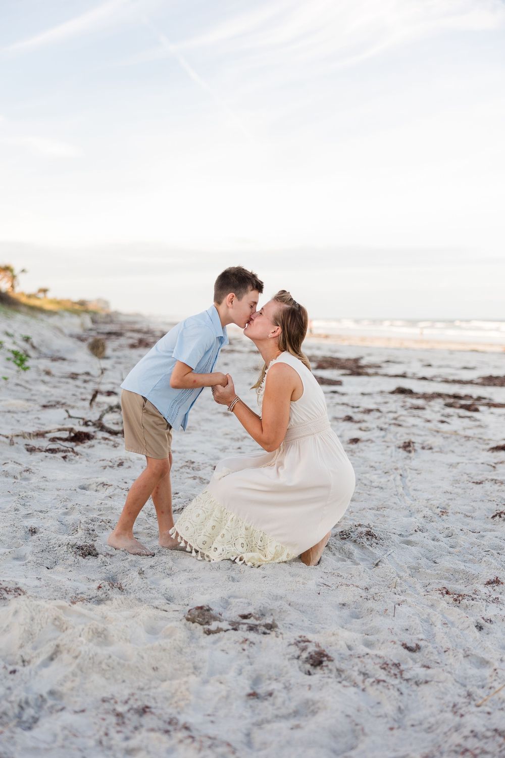 A playful couple shares a moment together on a sandy beach at sunset.