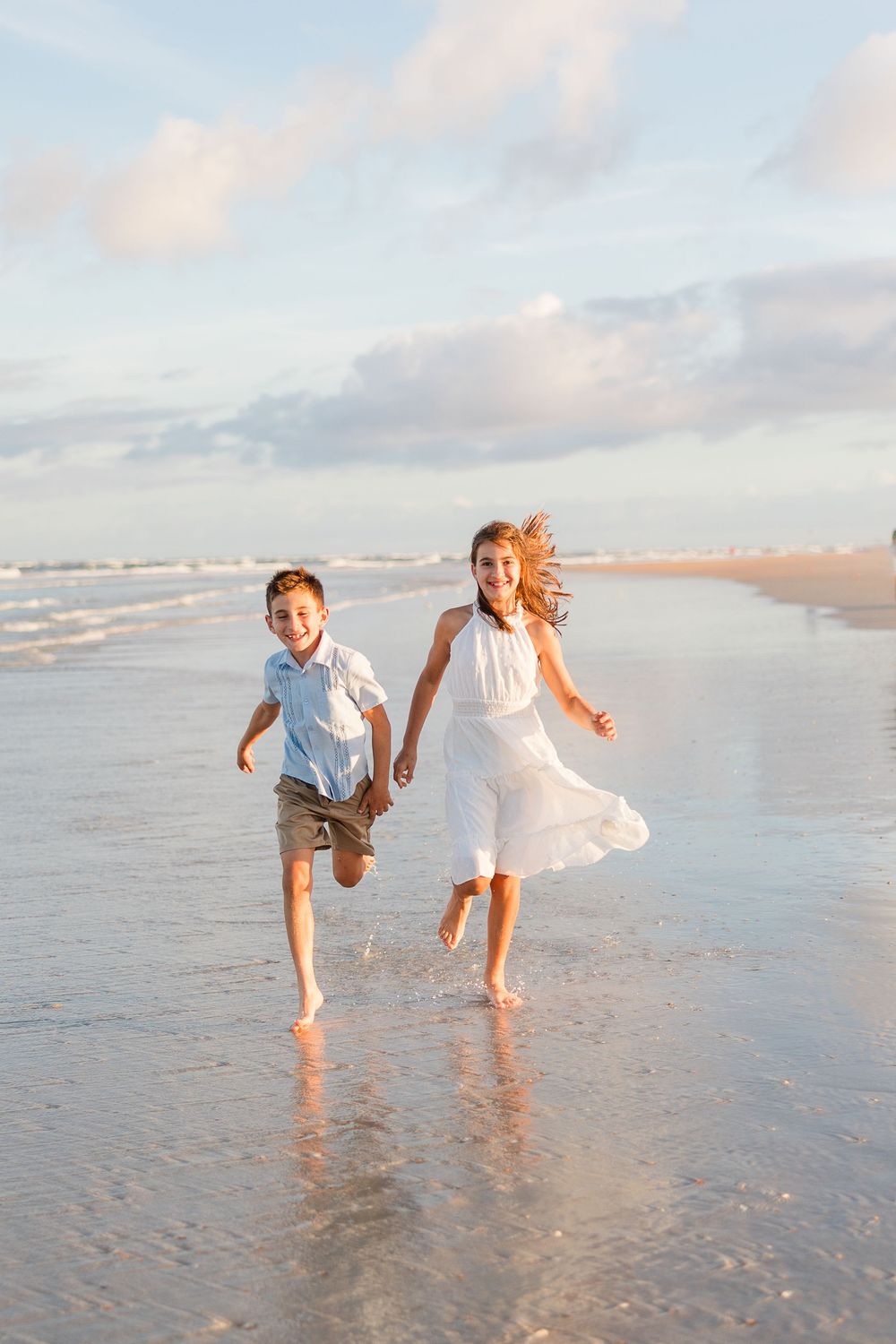 Children playing and splashing in the shallow ocean water at sunset.