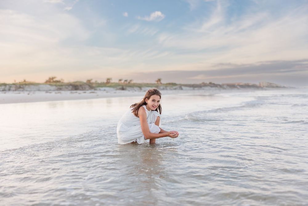 People wading and playing in the ocean waves during a beach photoshoot.