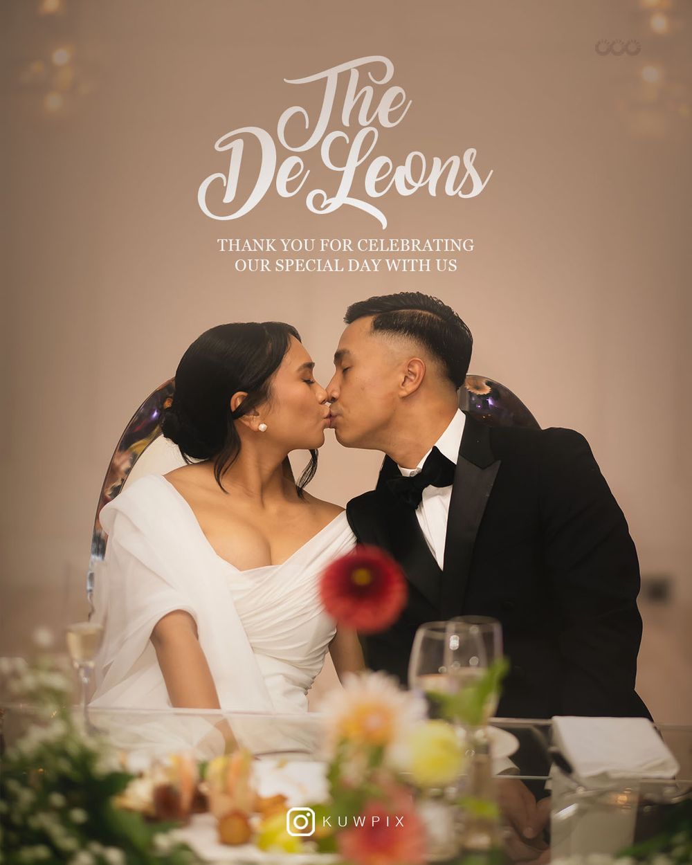 A romantic wedding couple shares an intimate kiss at their reception table with soft lighting and floral decor.