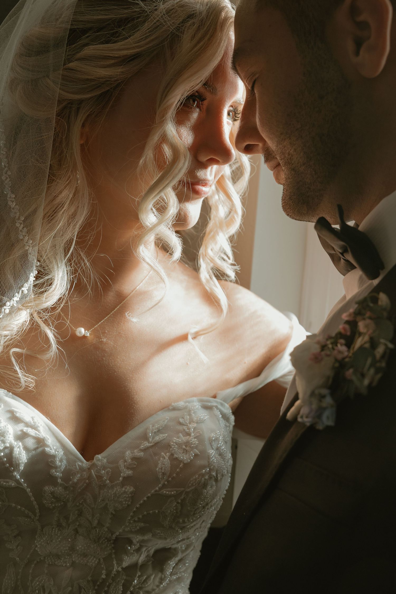 Romantic wedding portrait showing intimate moment between couple with bride in lace dress.