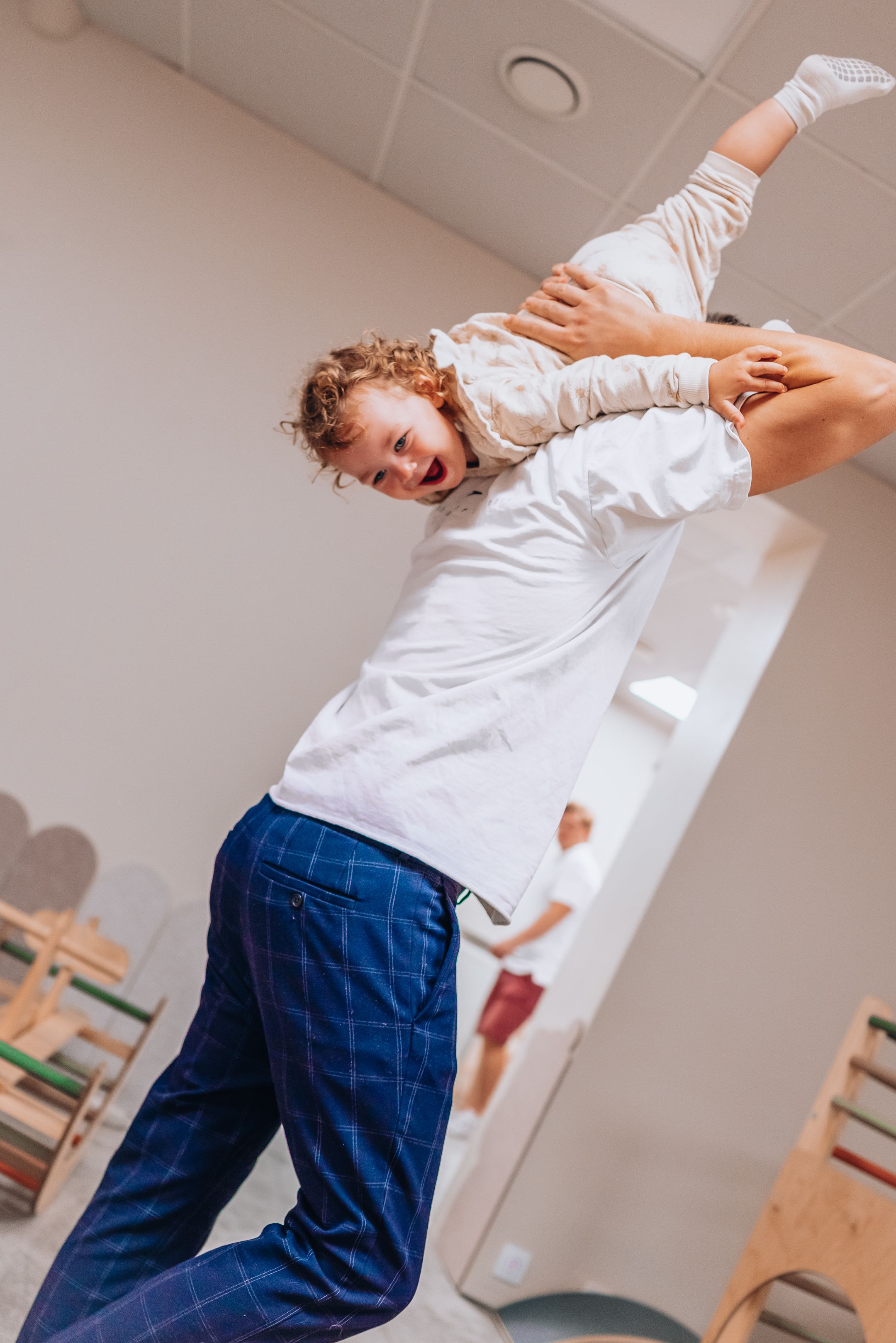 A person in a white shirt and blue plaid pants jumps energetically in an indoor space.