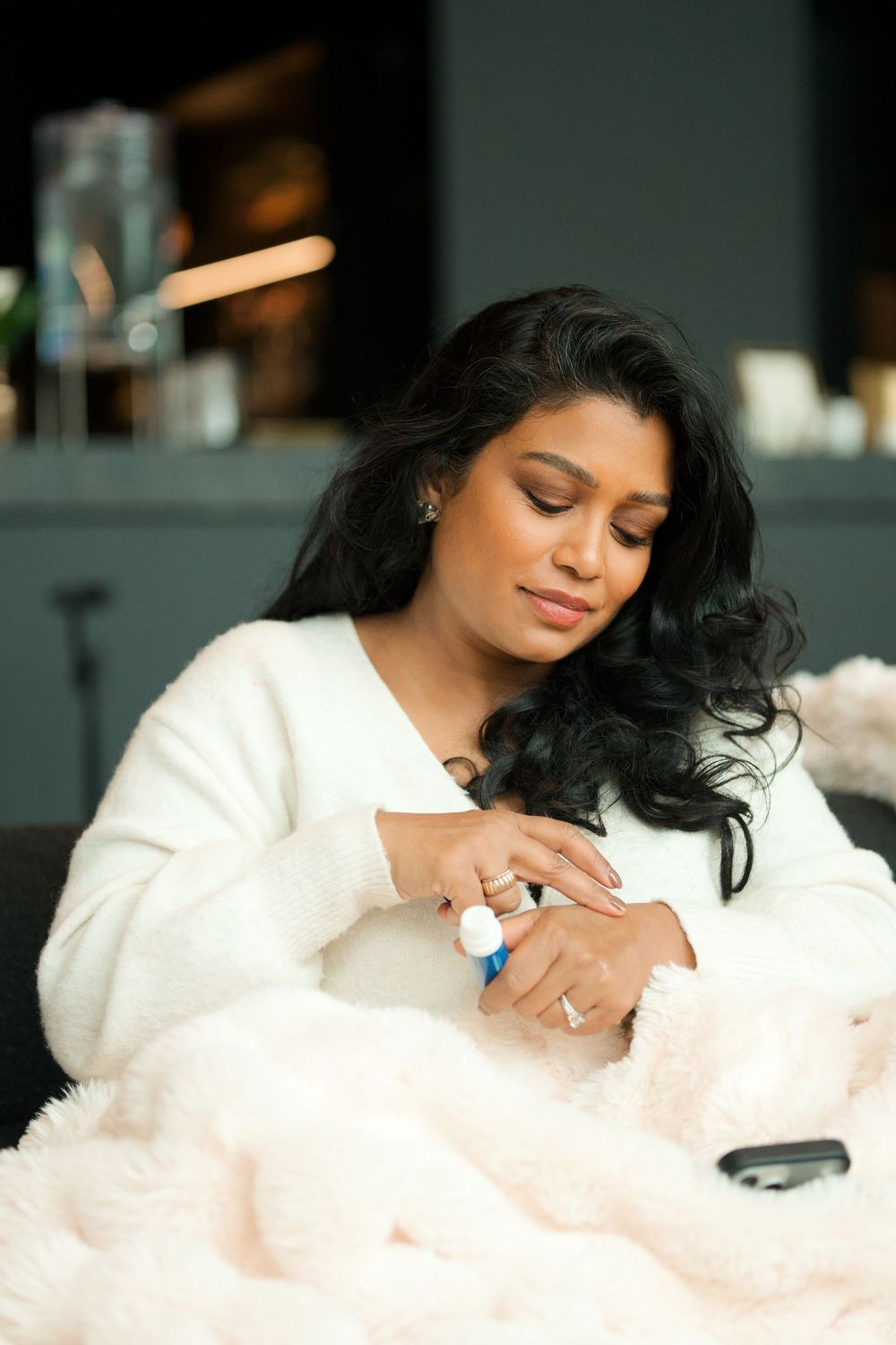 A person in a white blazer lays on a fluffy cloud-like surface with dark hair cascading down in a dreamy pose.