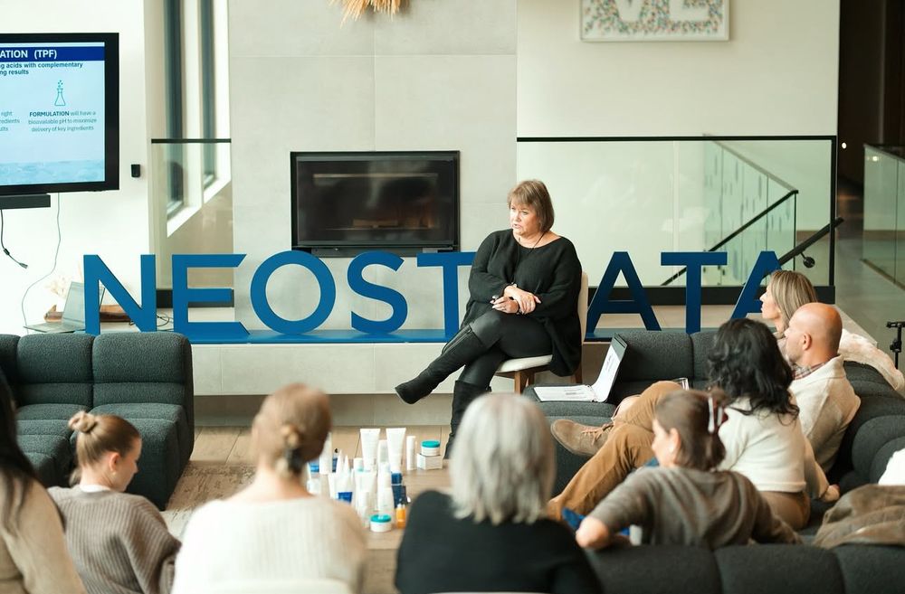 Business professionals seated in rows listen attentively during a corporate presentation in a modern office space. Neostrata community trip.