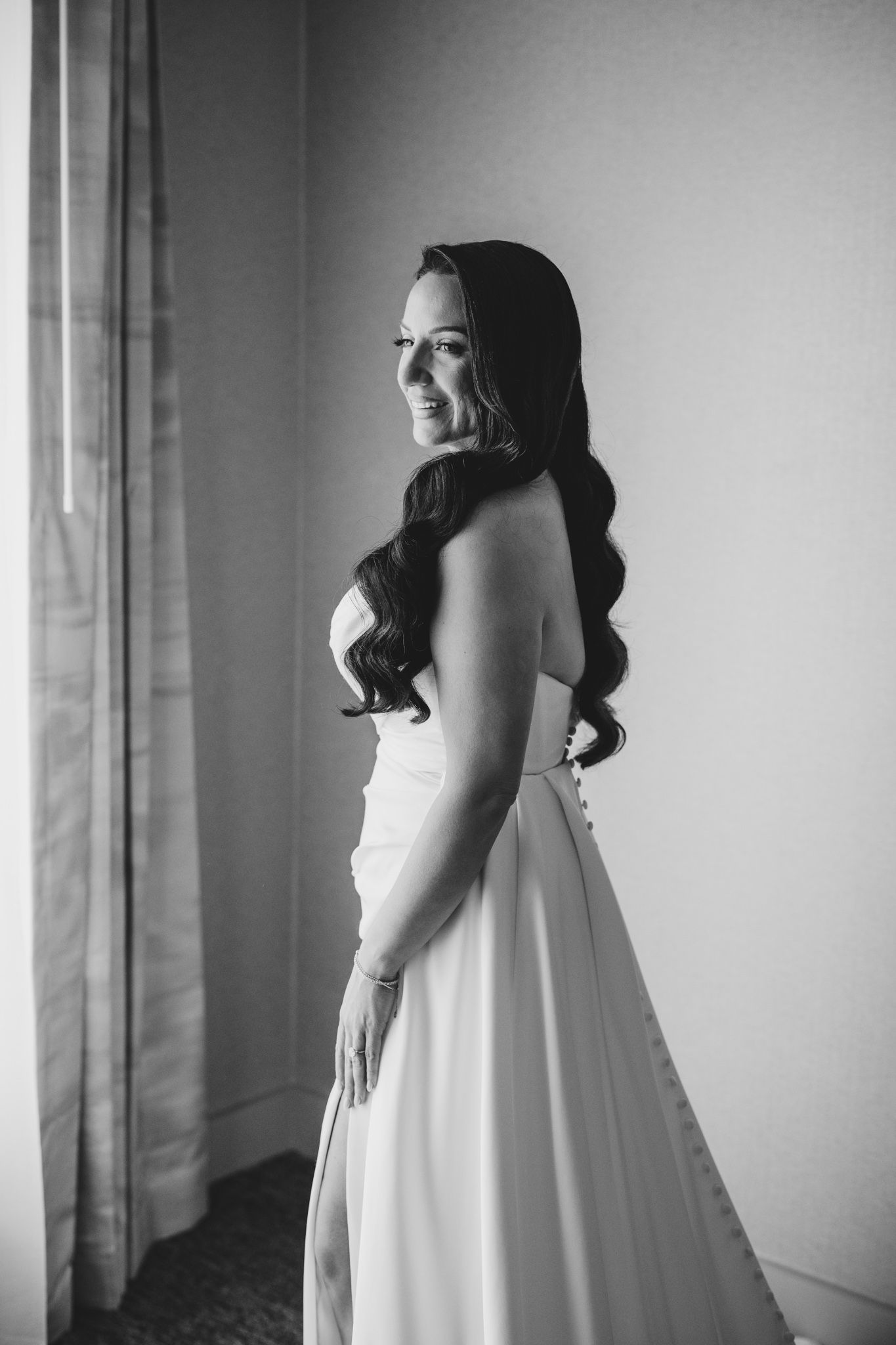 Black and white portrait of a bride in a strapless wedding gown with long dark waves.