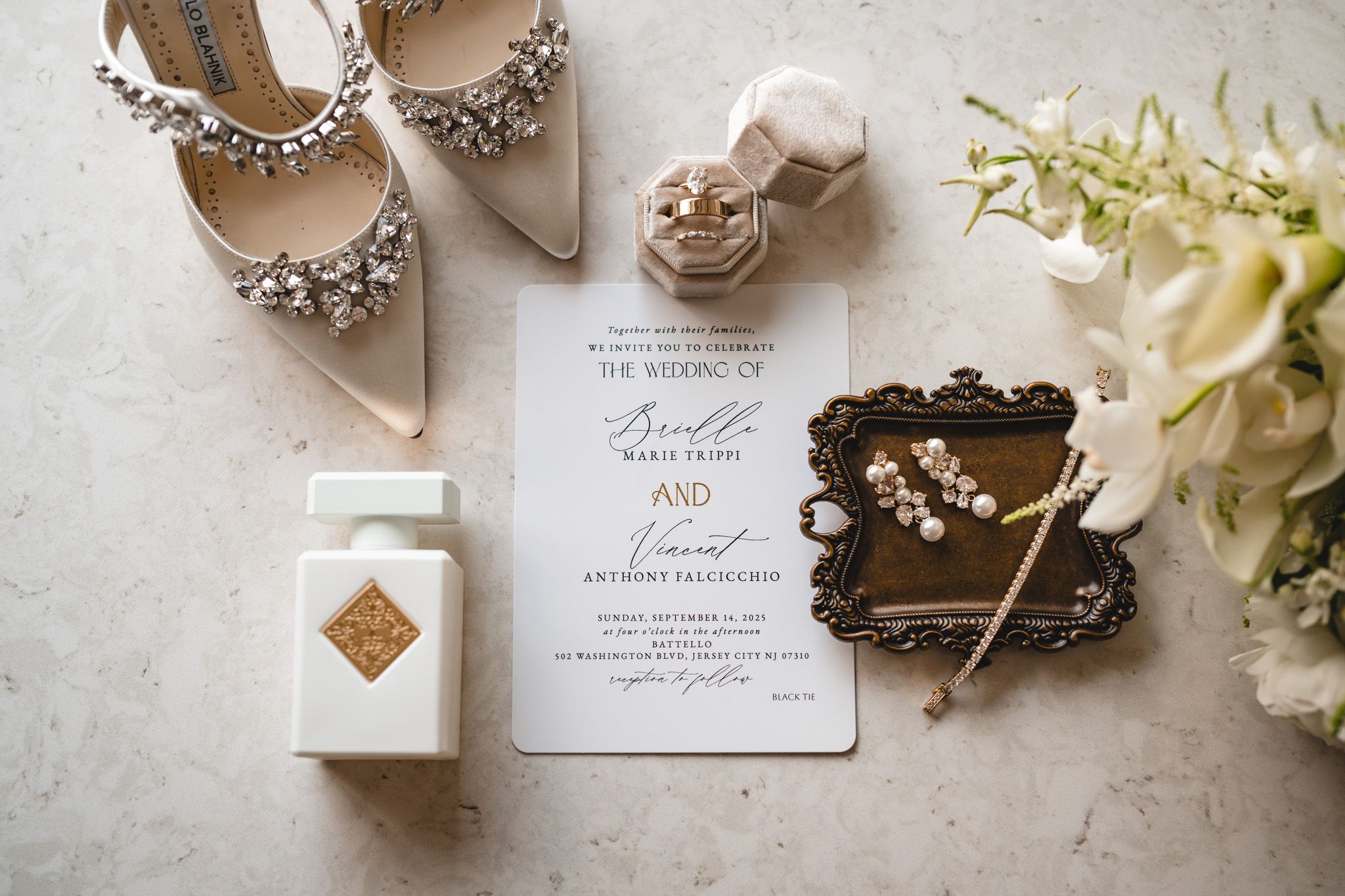 Wedding accessories including elegant shoes, invitations, and jewelry arranged on a light surface.