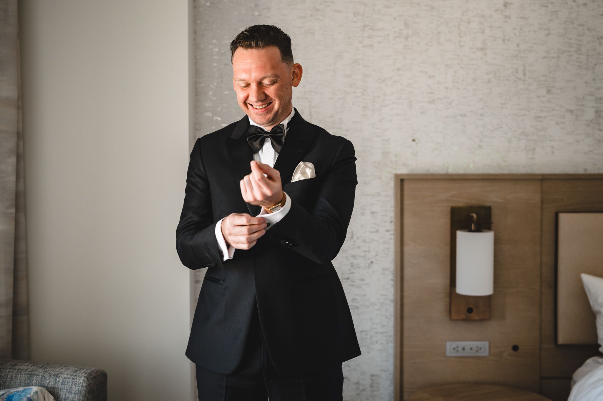 People in suits share candid moments while getting ready in a hotel room.
