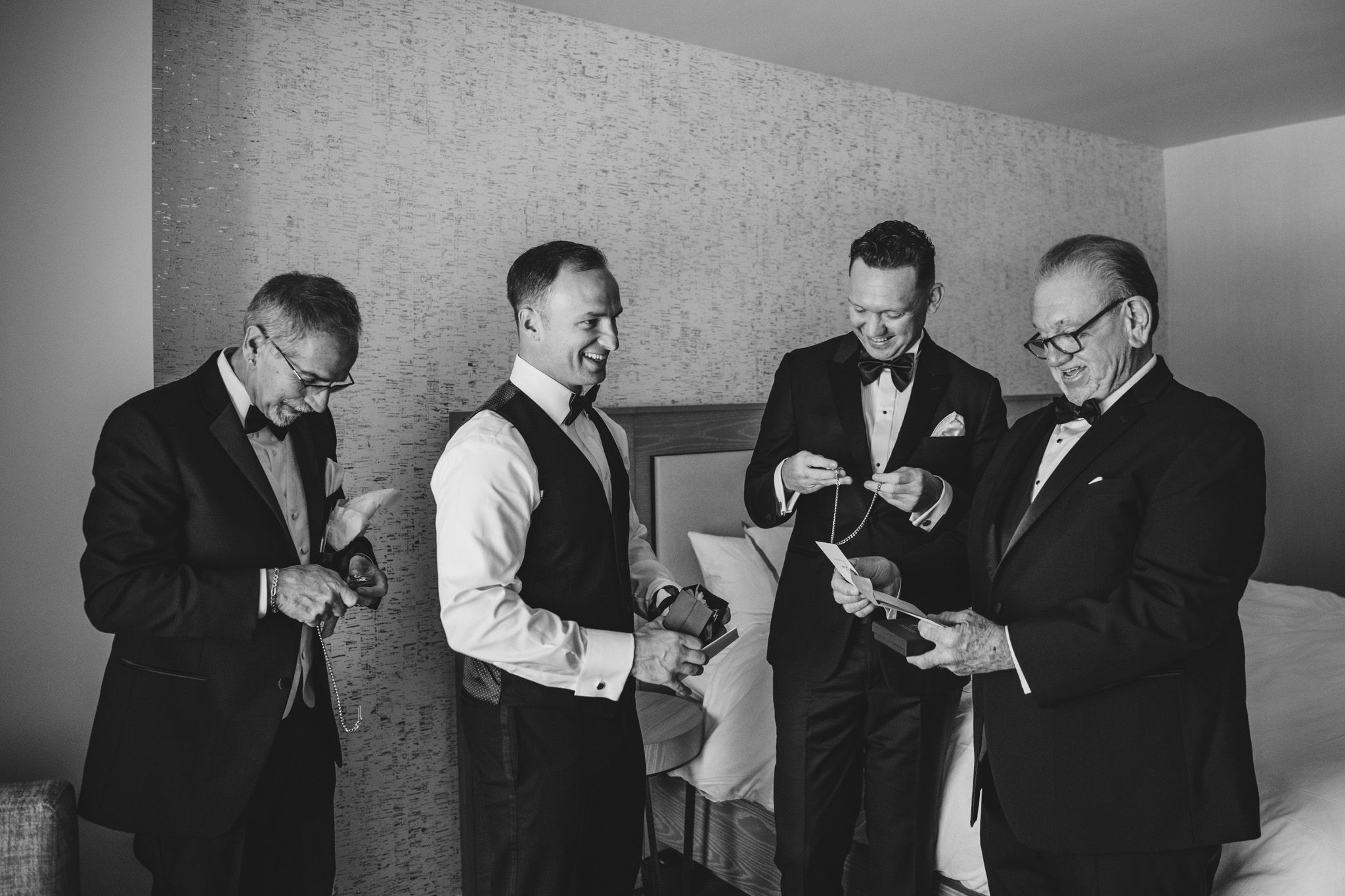 Groomsmen getting ready in black and white formal attire before a wedding ceremony.