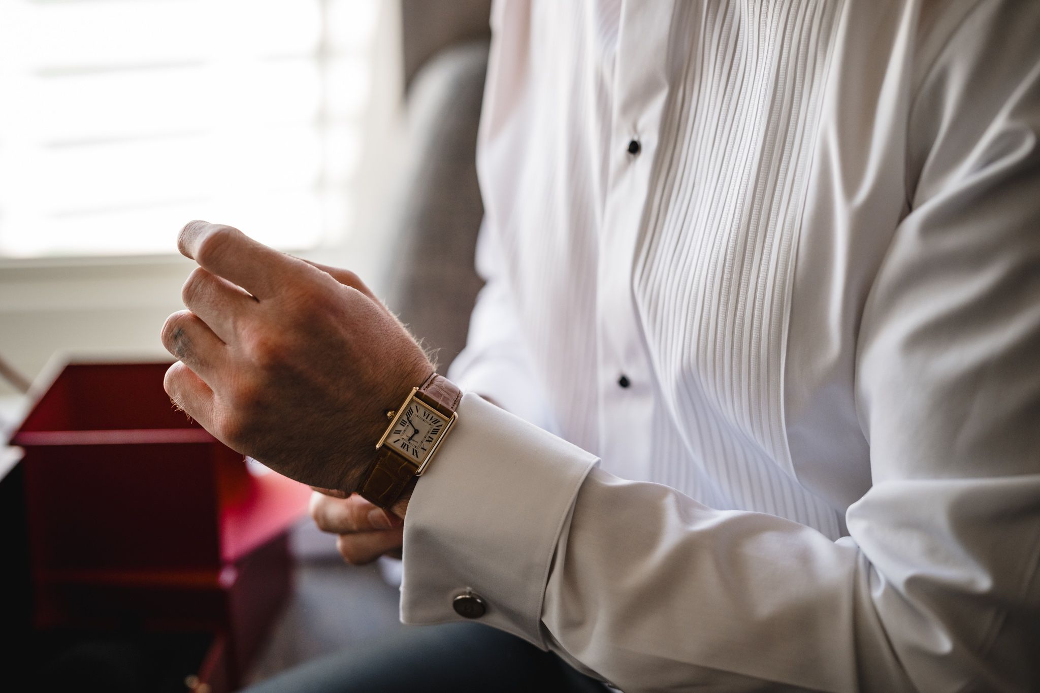 Close-up shot of someone in formal attire adjusting cufflinks and accessories.