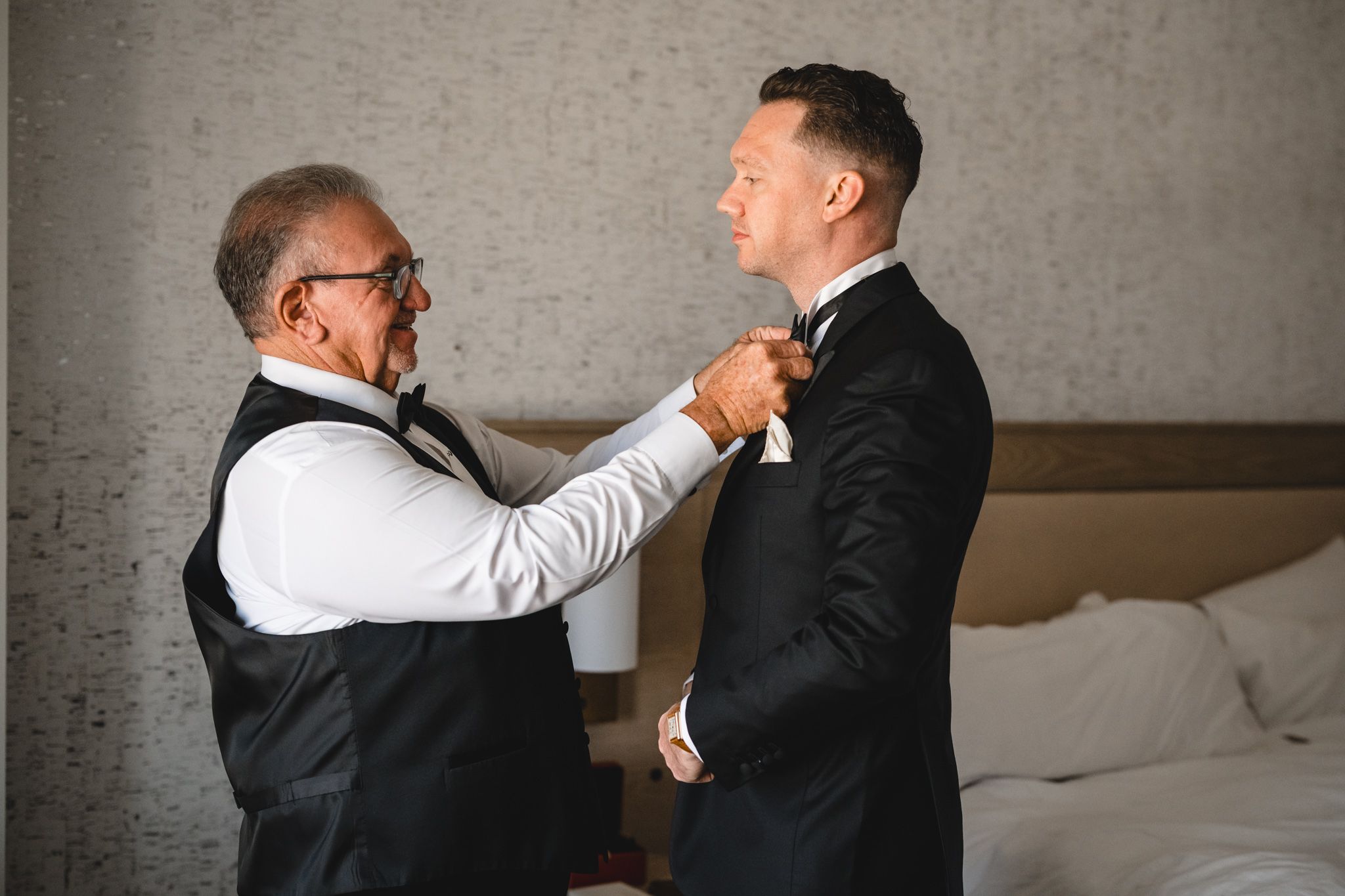 Two people in suits share an emotional moment while getting ready.