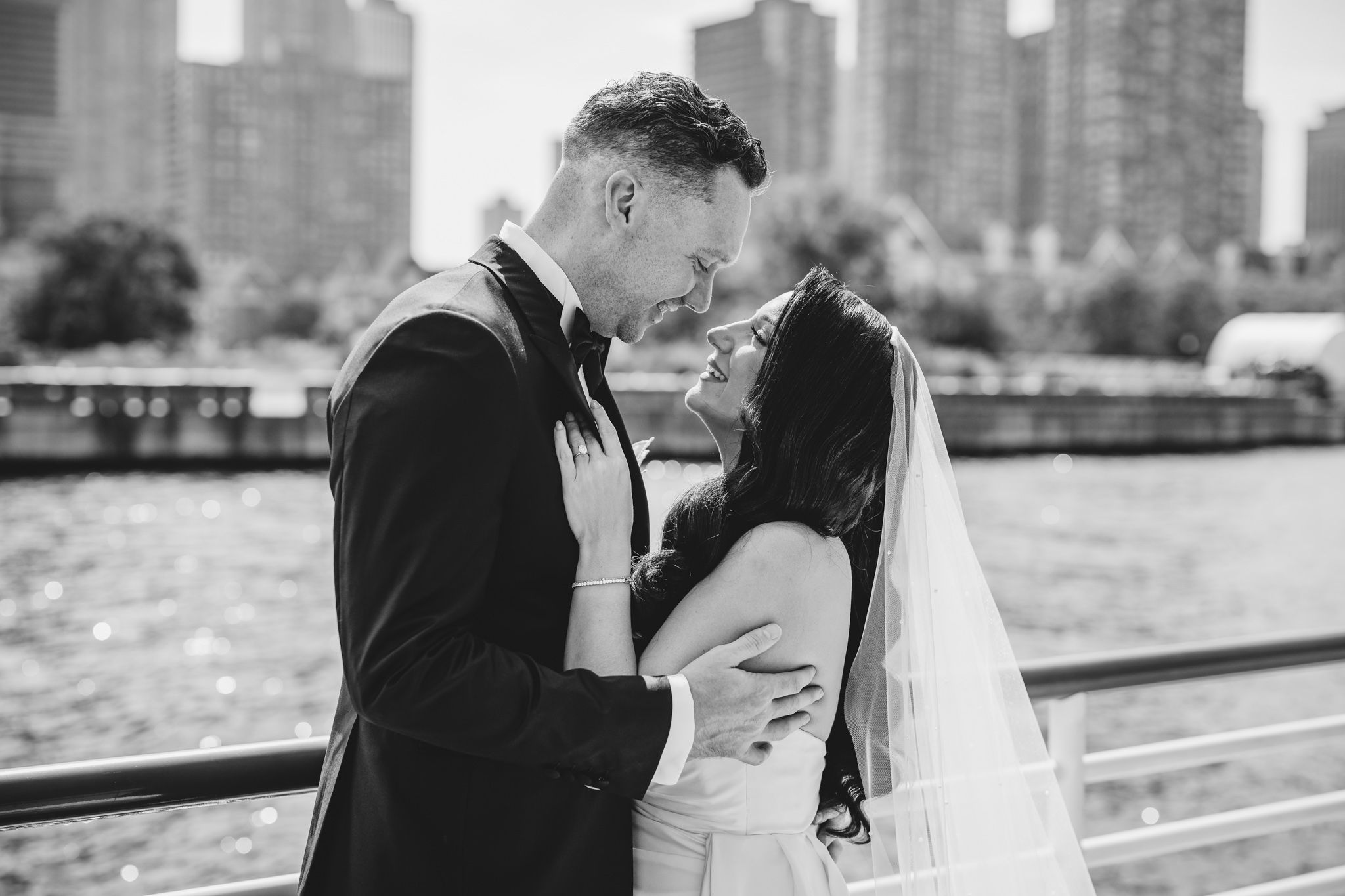 Wedding couple shares intimate moments on pier with urban backdrop.