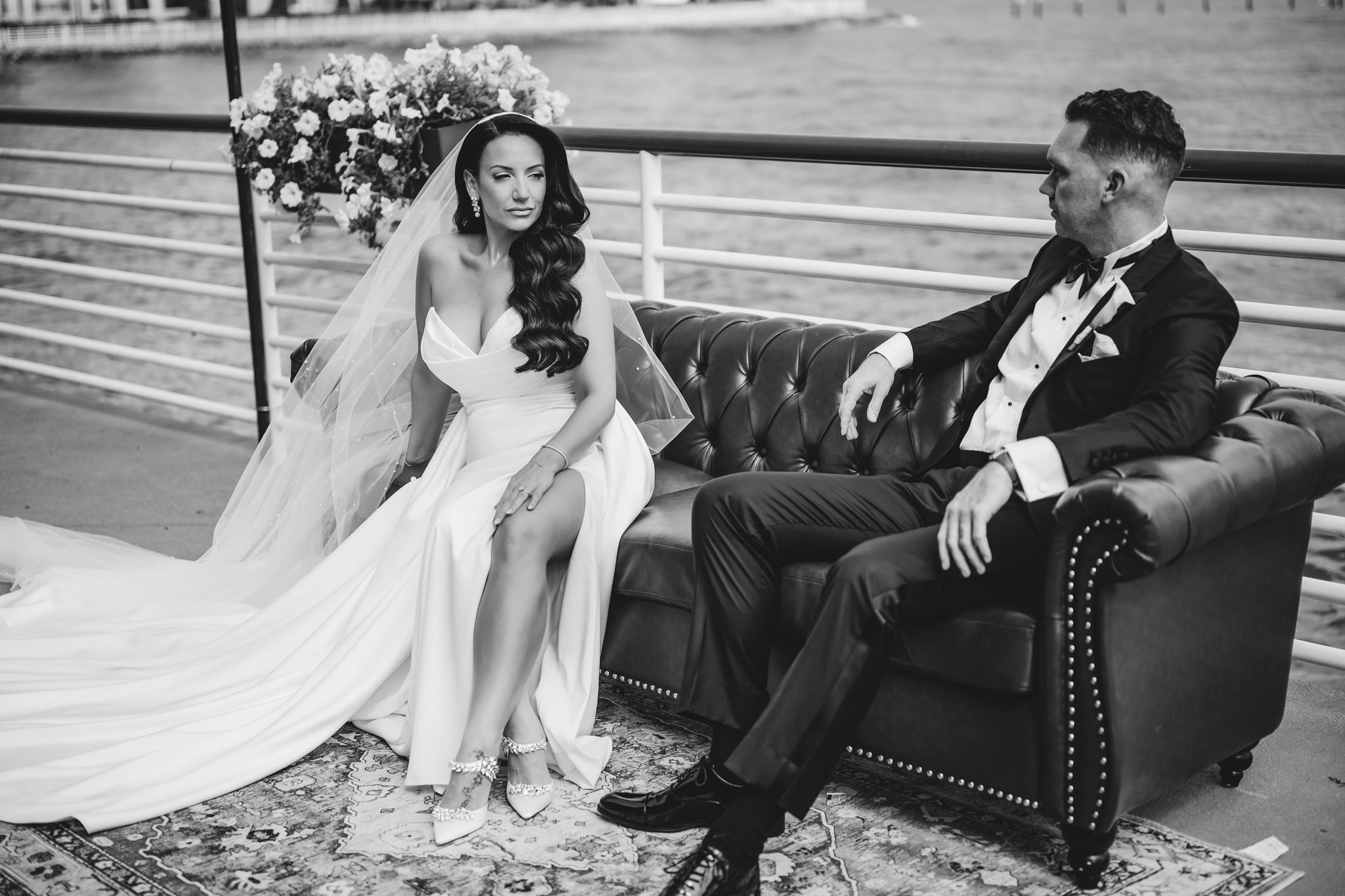 Wedding couple poses on vintage furniture with waterfront views.