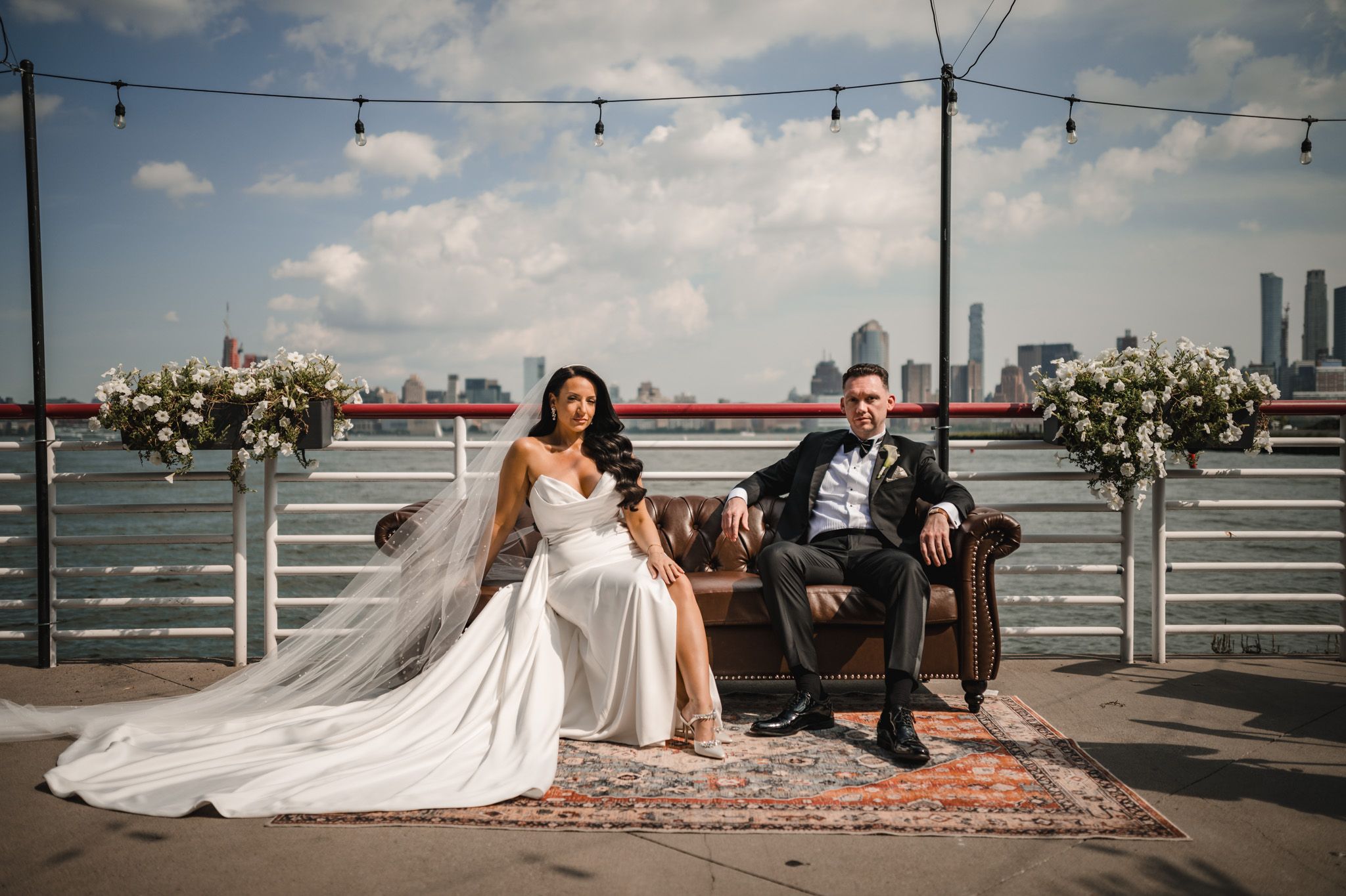 Elegant wedding photoshoot on pier with string lights and city views.