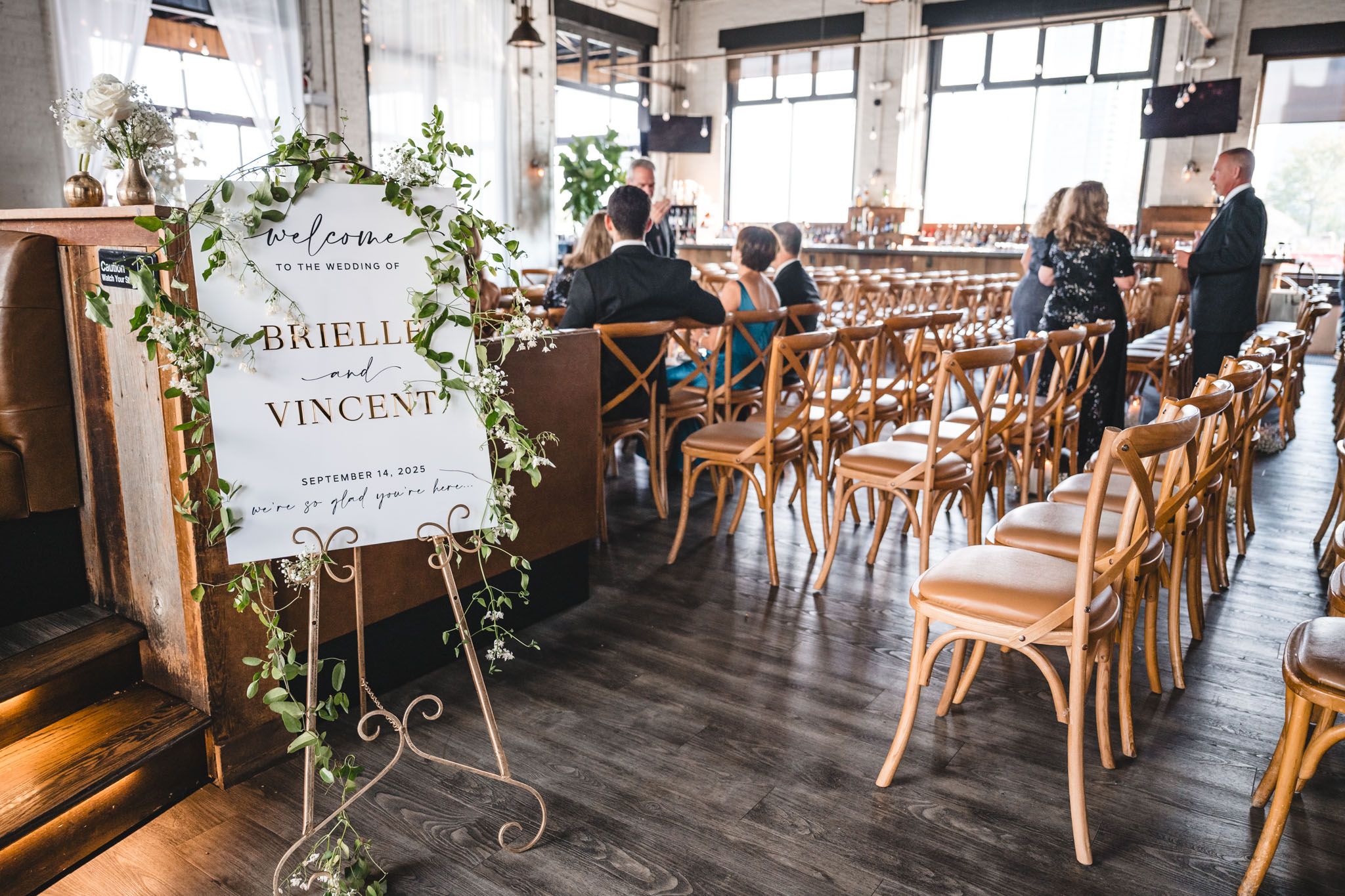 Wedding venue decorated with wooden chairs and floral arrangements in an industrial-style space.