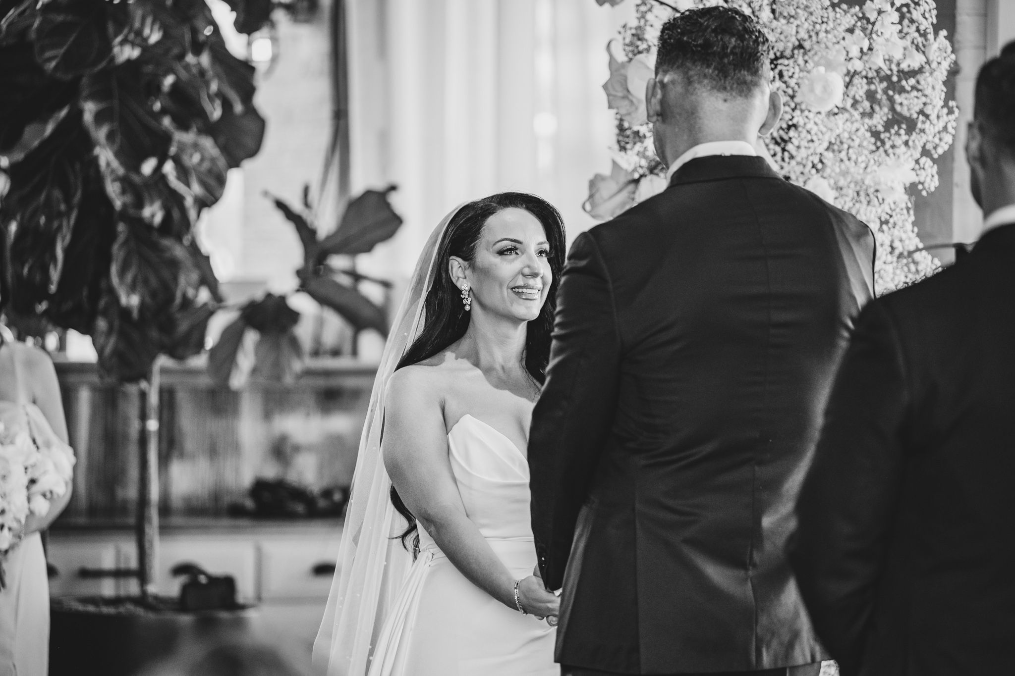 A black and white wedding ceremony moment captured during the exchange of vows in an elegant indoor venue.