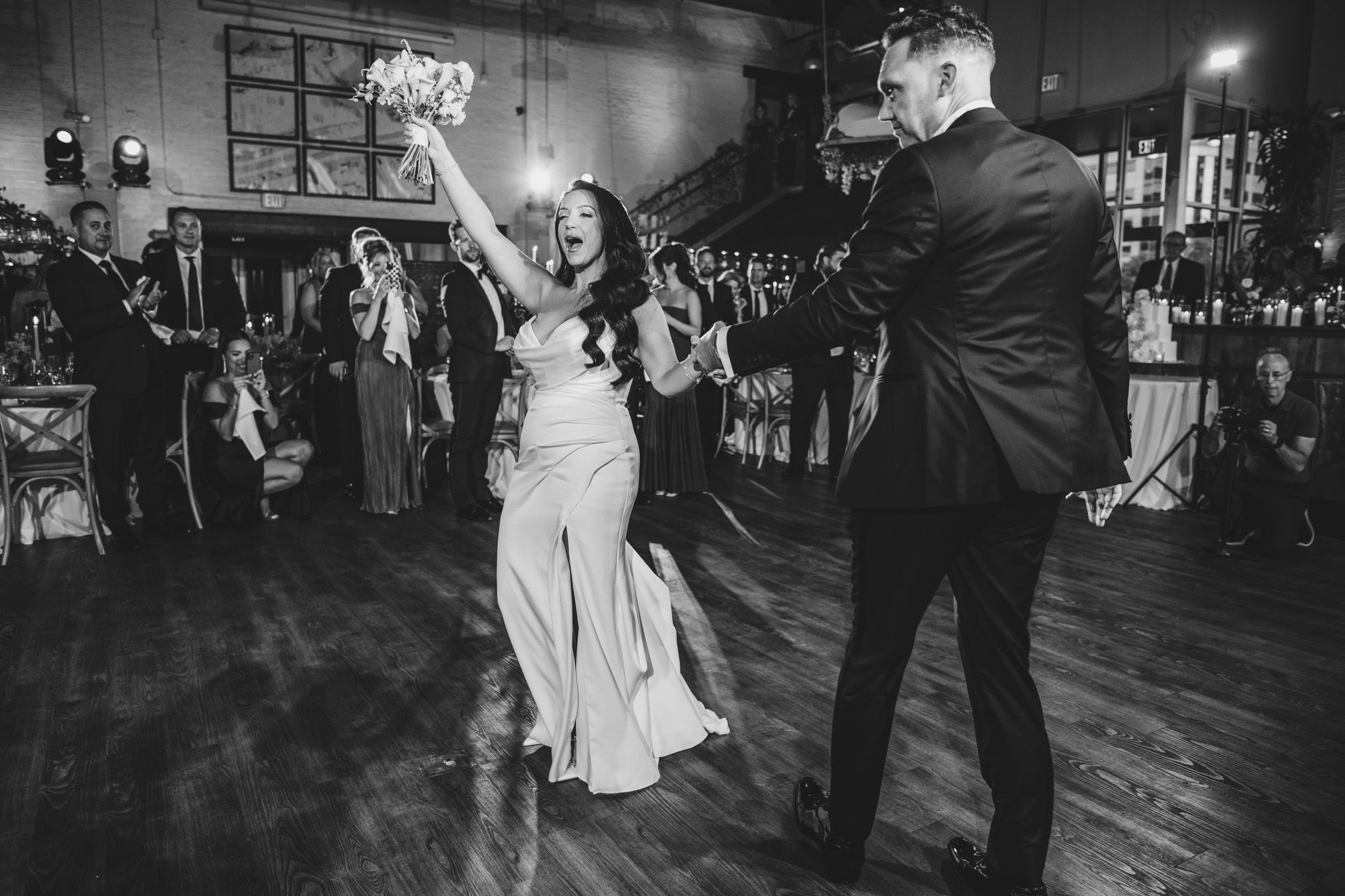 Black and white photo of couples dancing at an elegant indoor celebration.