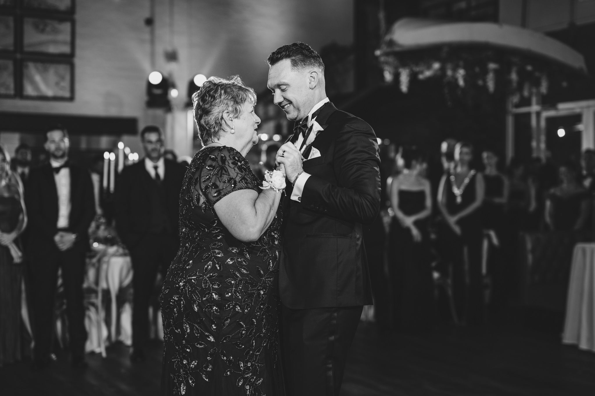 Wedding reception dance floor filled with guests enjoying a celebration in black and white photography.