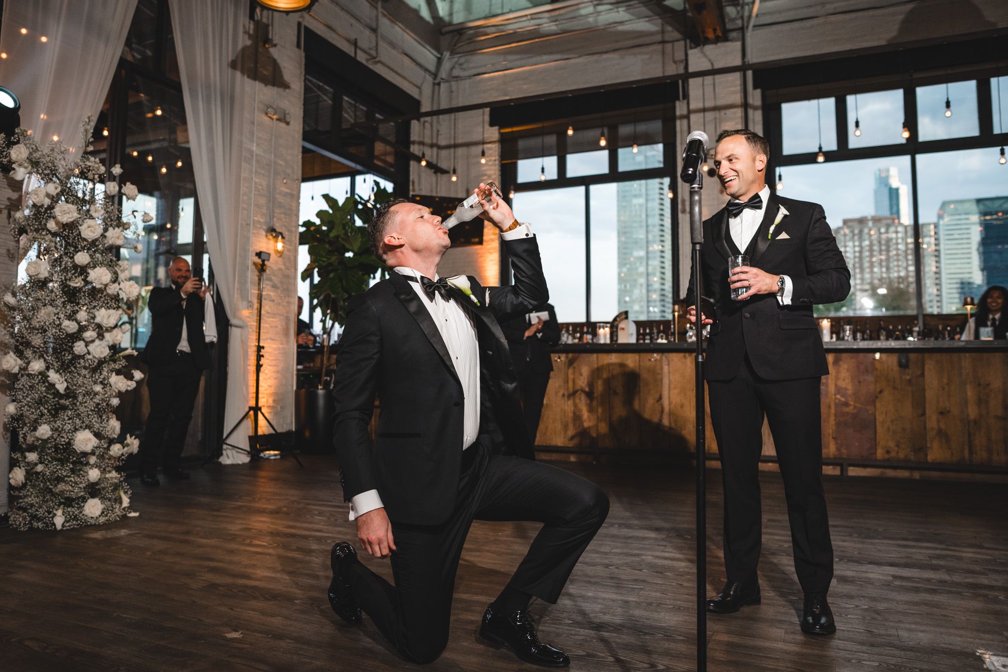 Elegant wedding reception venue with wooden floors and large windows overlooking city views.