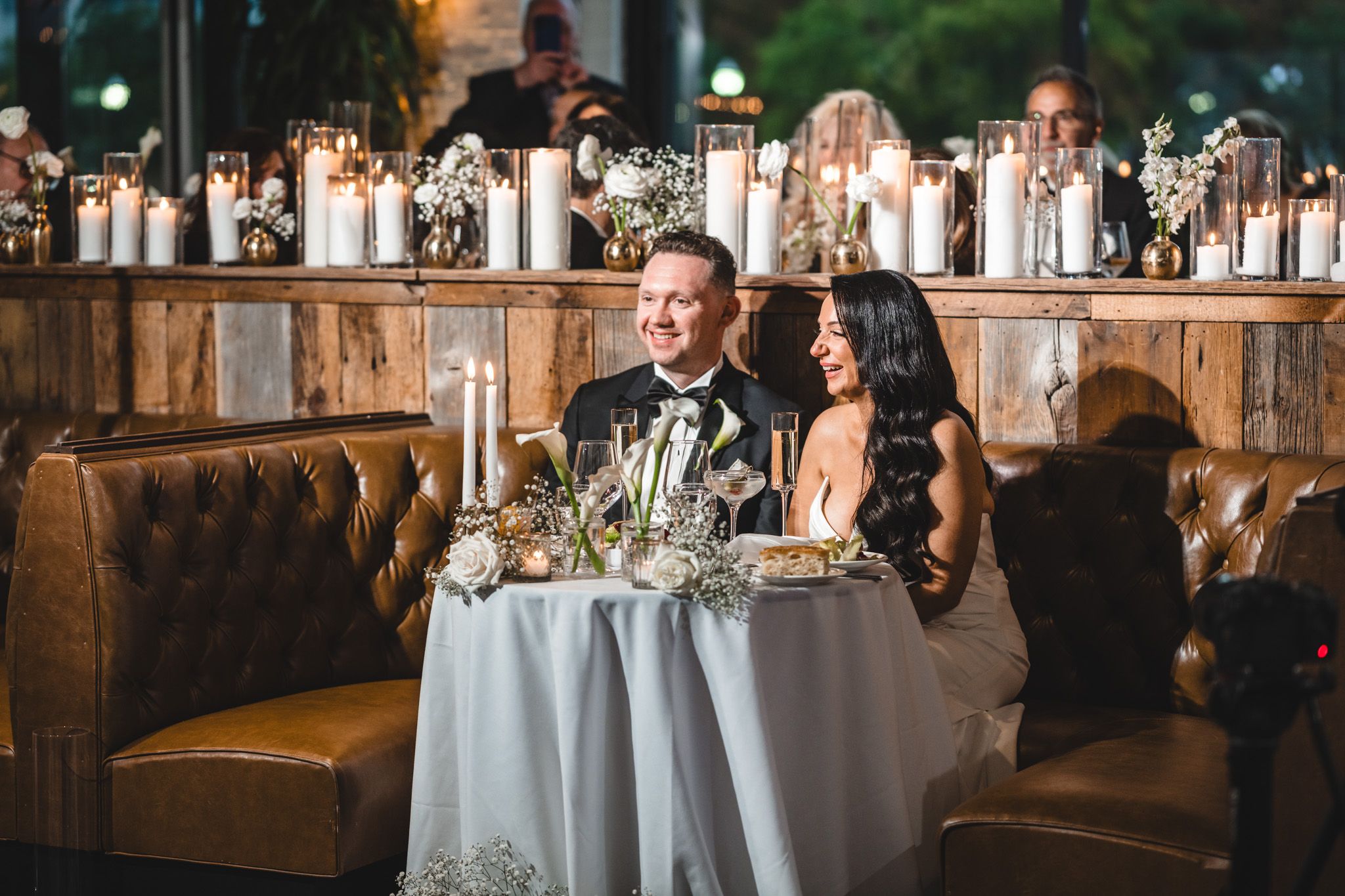 Elegant wedding reception setup with white tablecloths and rustic leather booth seating.