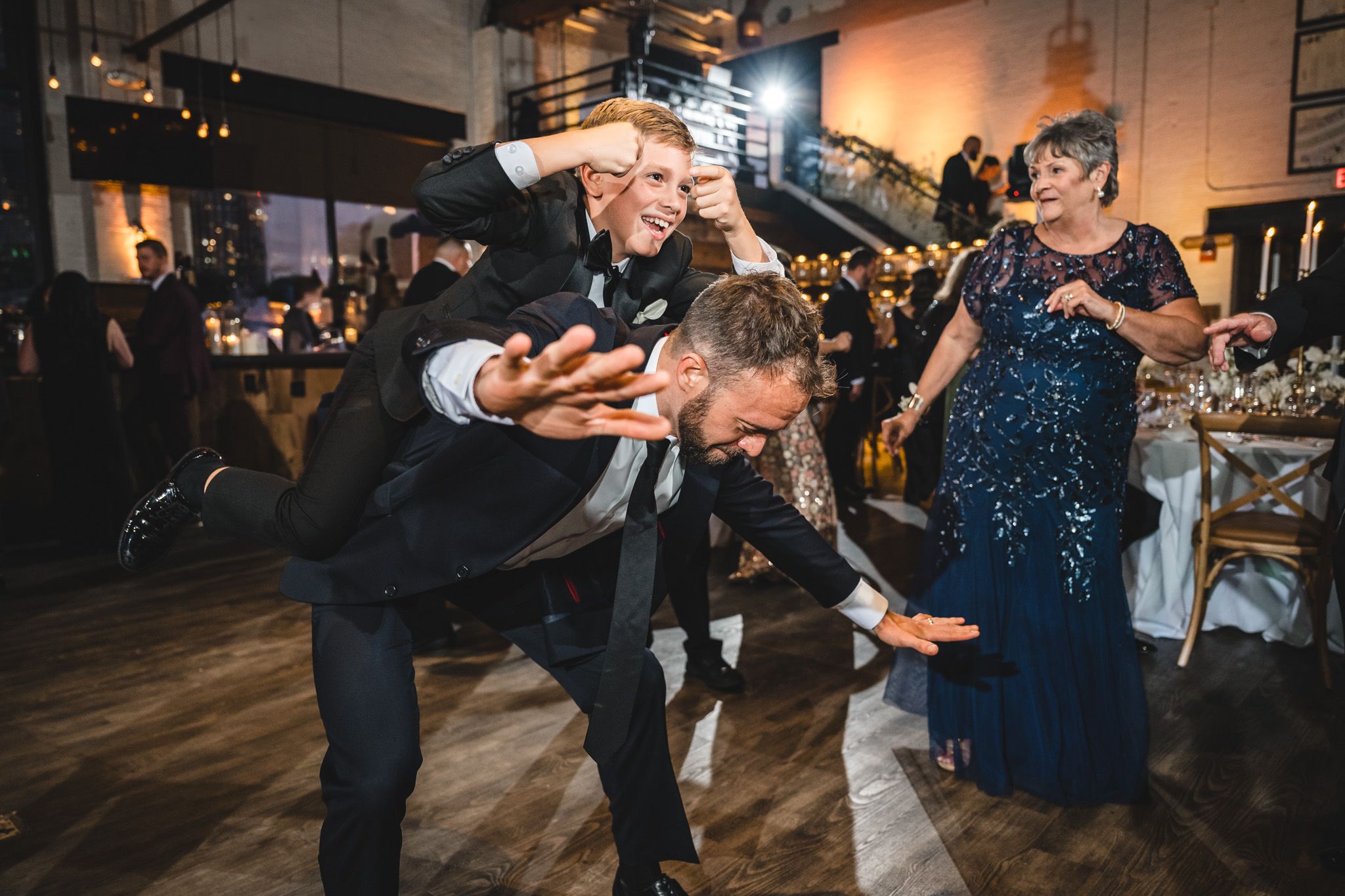 Wedding guests dancing and celebrating on a dimly lit dance floor during reception.