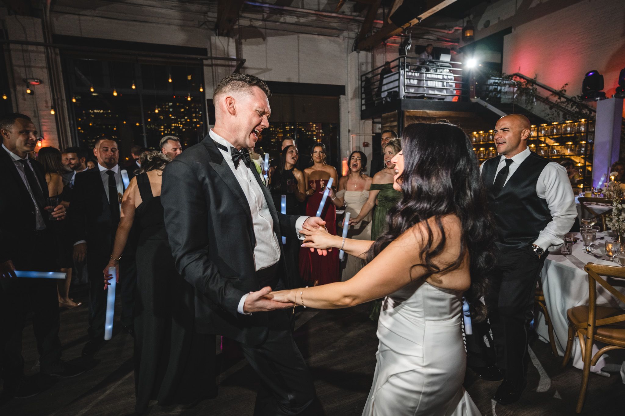 Wedding guests dance and celebrate on a dimly lit dance floor at an elegant evening reception.