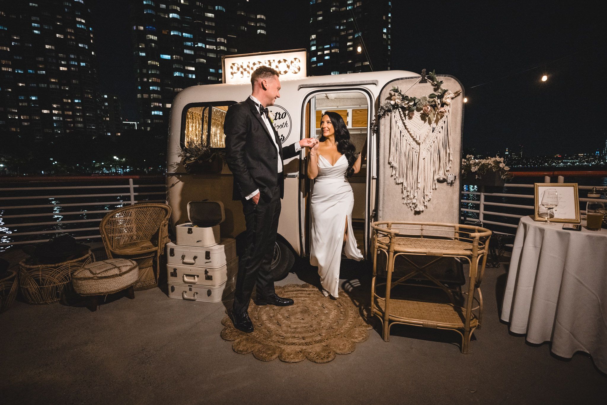 Couples dancing together at an elegant evening wedding reception with city lights visible through windows.