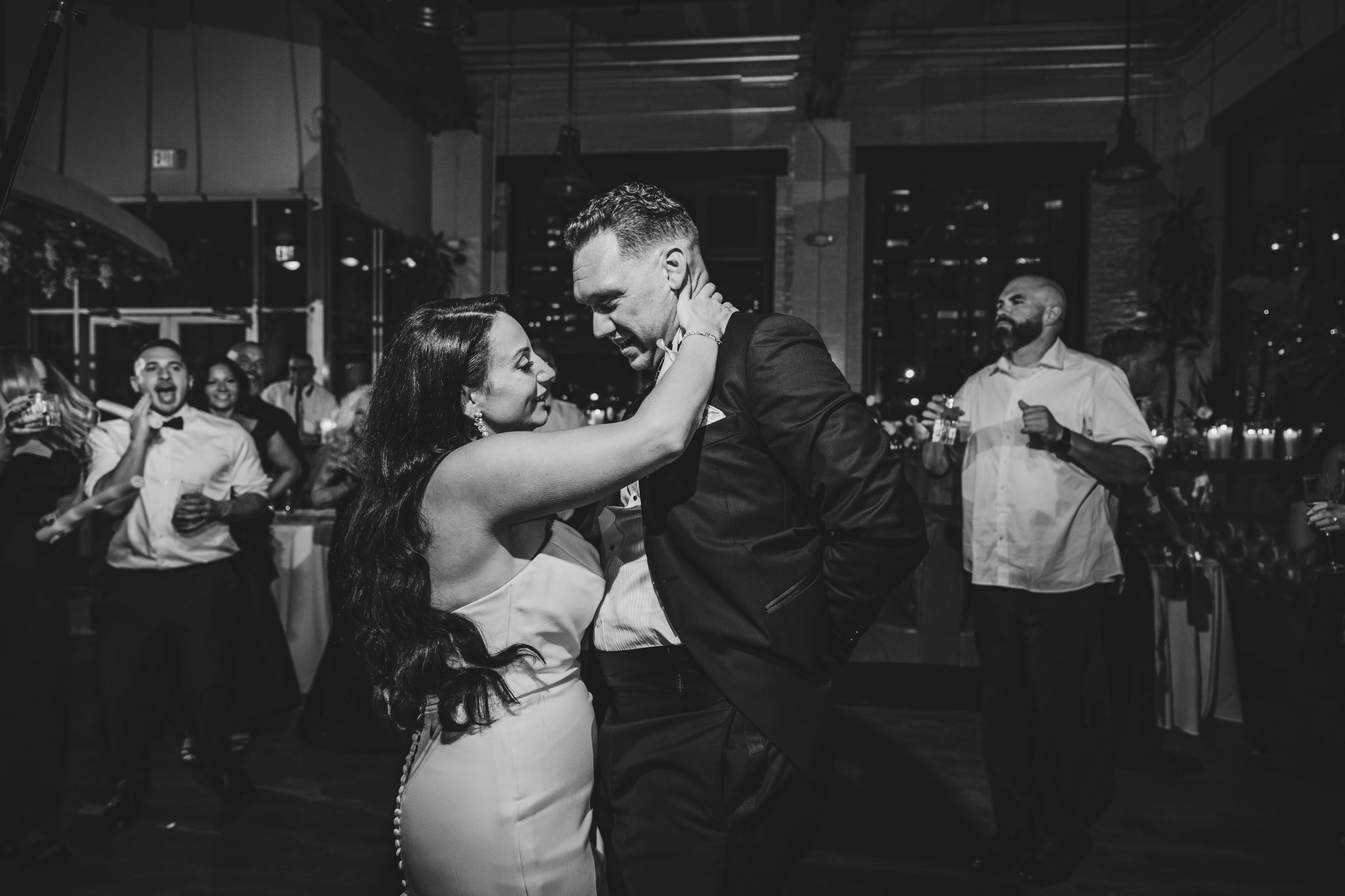 Black and white photo of couples dancing at an elegant indoor wedding reception.