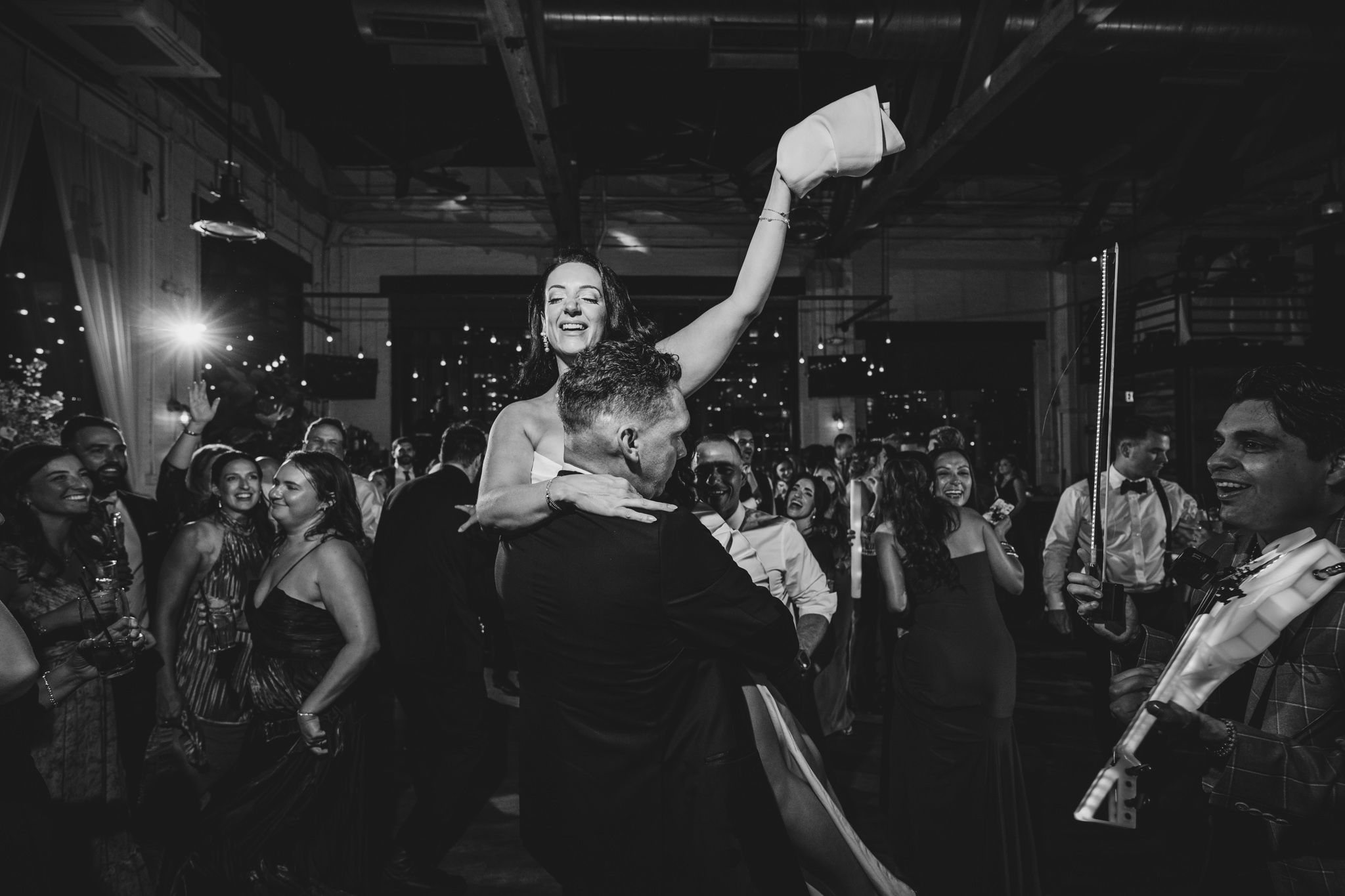 Energetic dancing and celebration captured in black and white at a wedding reception.