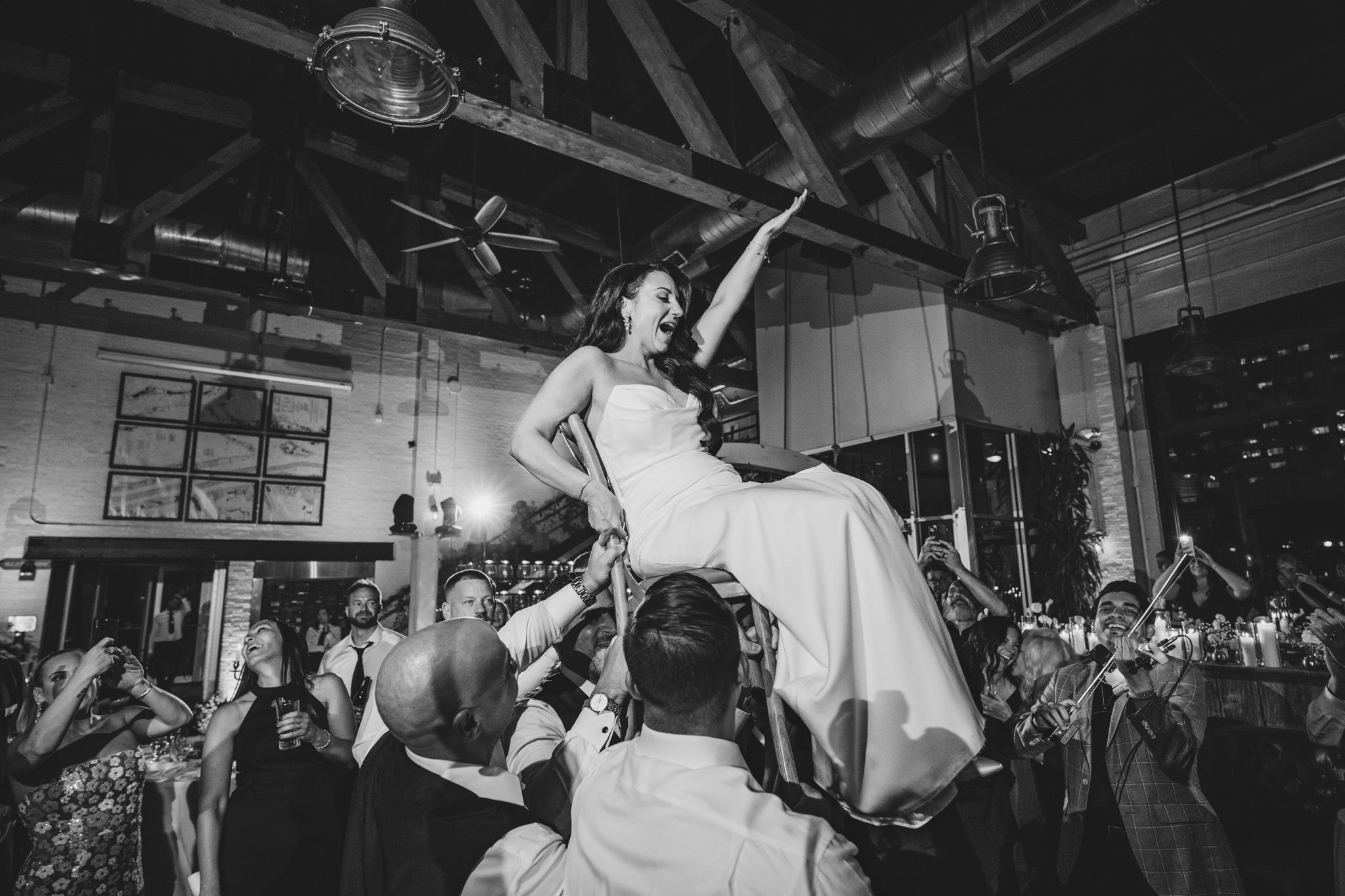 Wedding guests raise their hands in celebration during a lively dance floor moment.