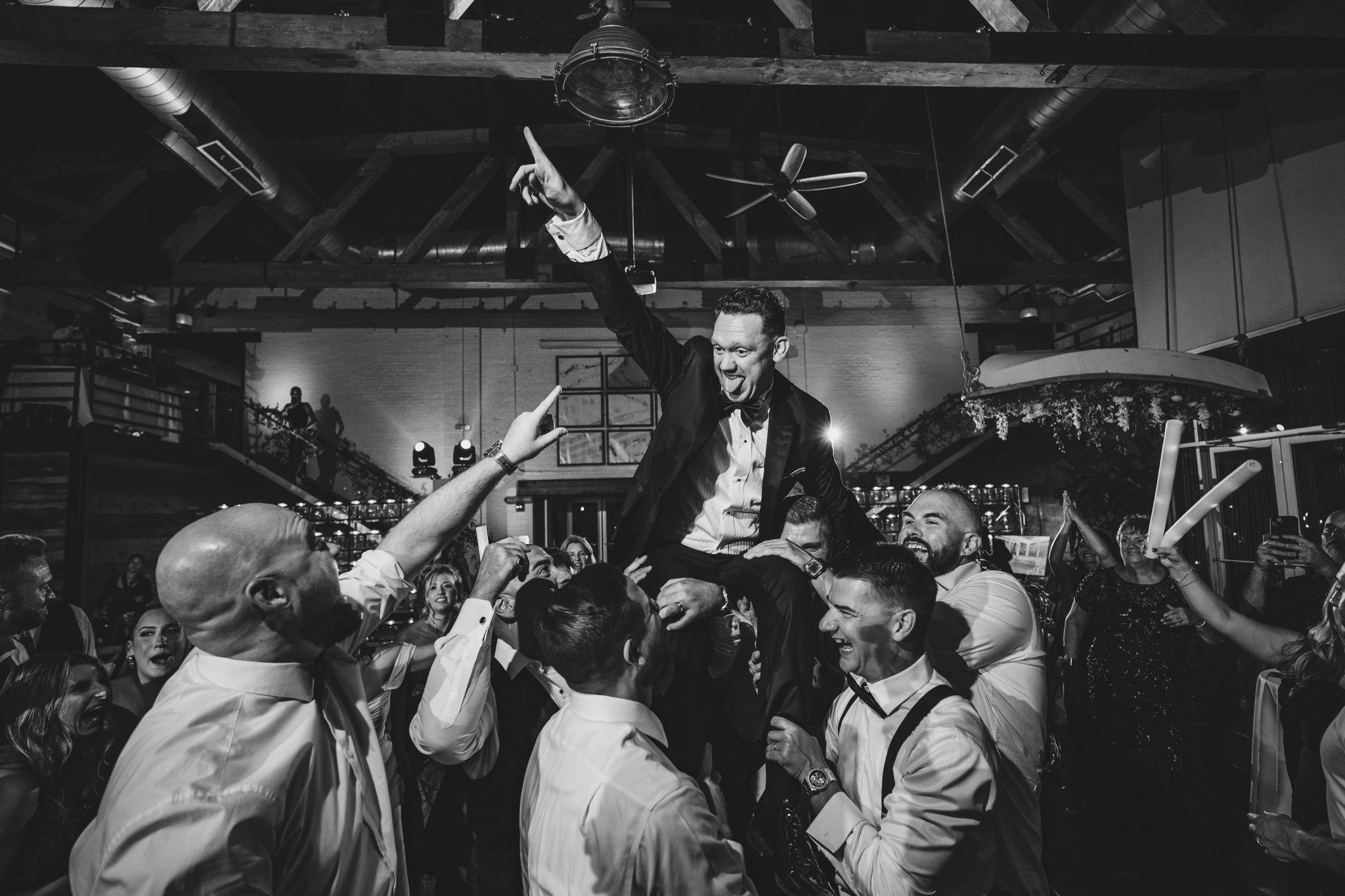 Silhouettes of wedding guests dancing with hands raised during an energetic reception celebration.