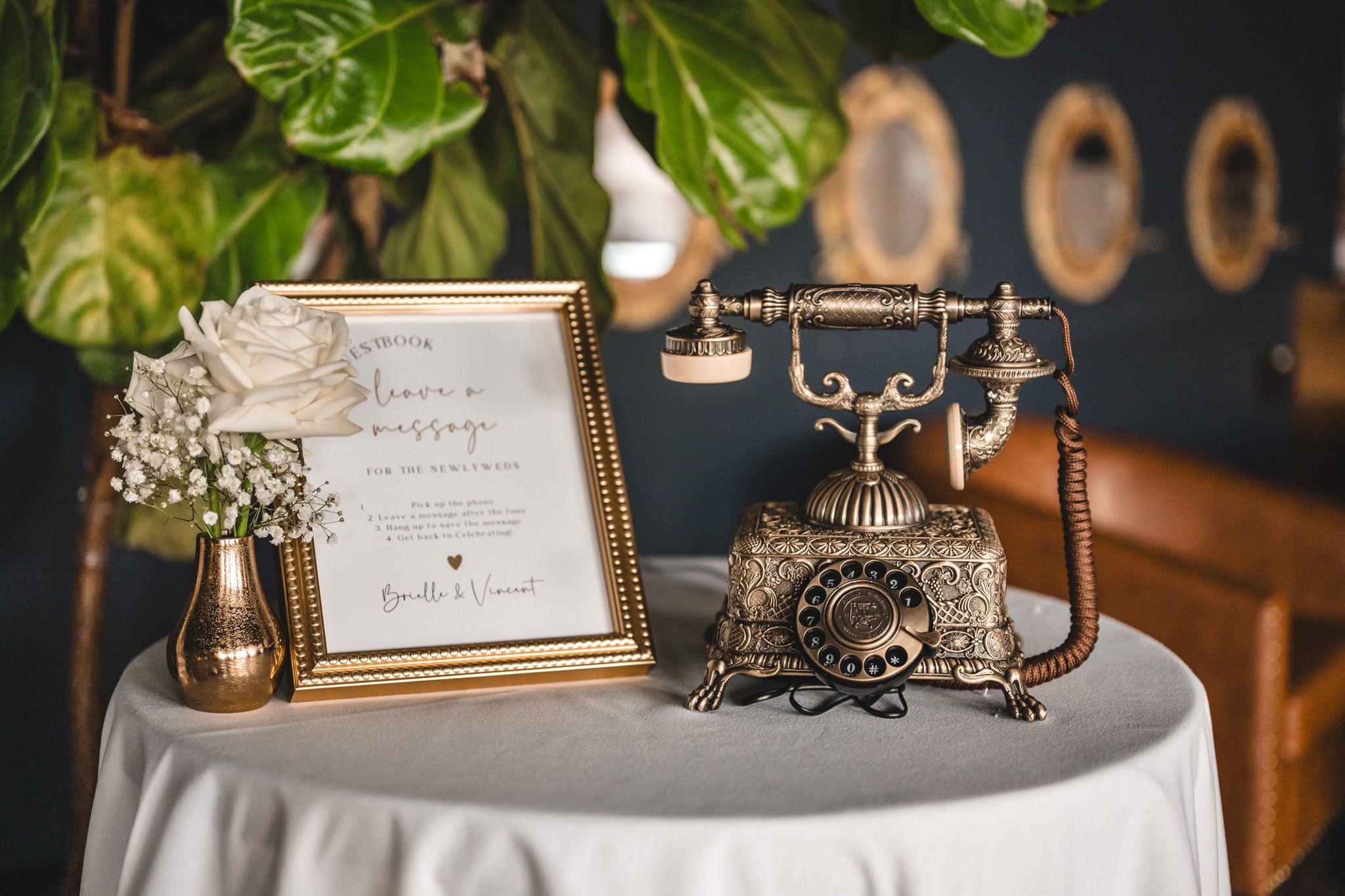 Vintage rotary telephone and framed wedding details on white linen covered table.
