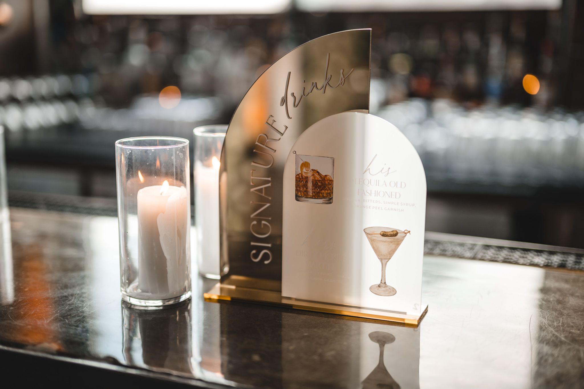 Elegant cocktail glasses and drinks arranged on a dark bar counter with moody lighting.