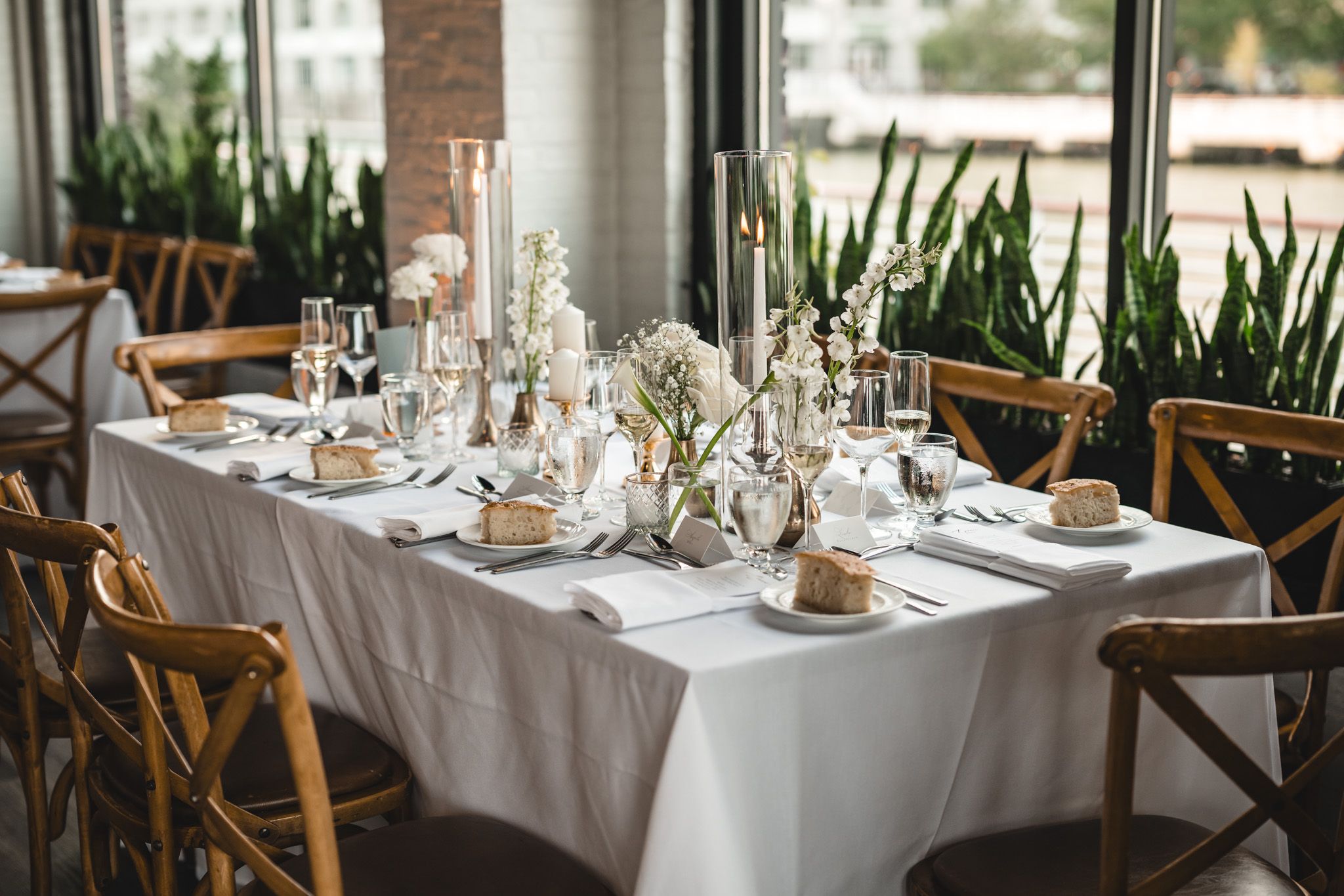 Modern restaurant interior with white tablecloths and natural lighting from large windows.