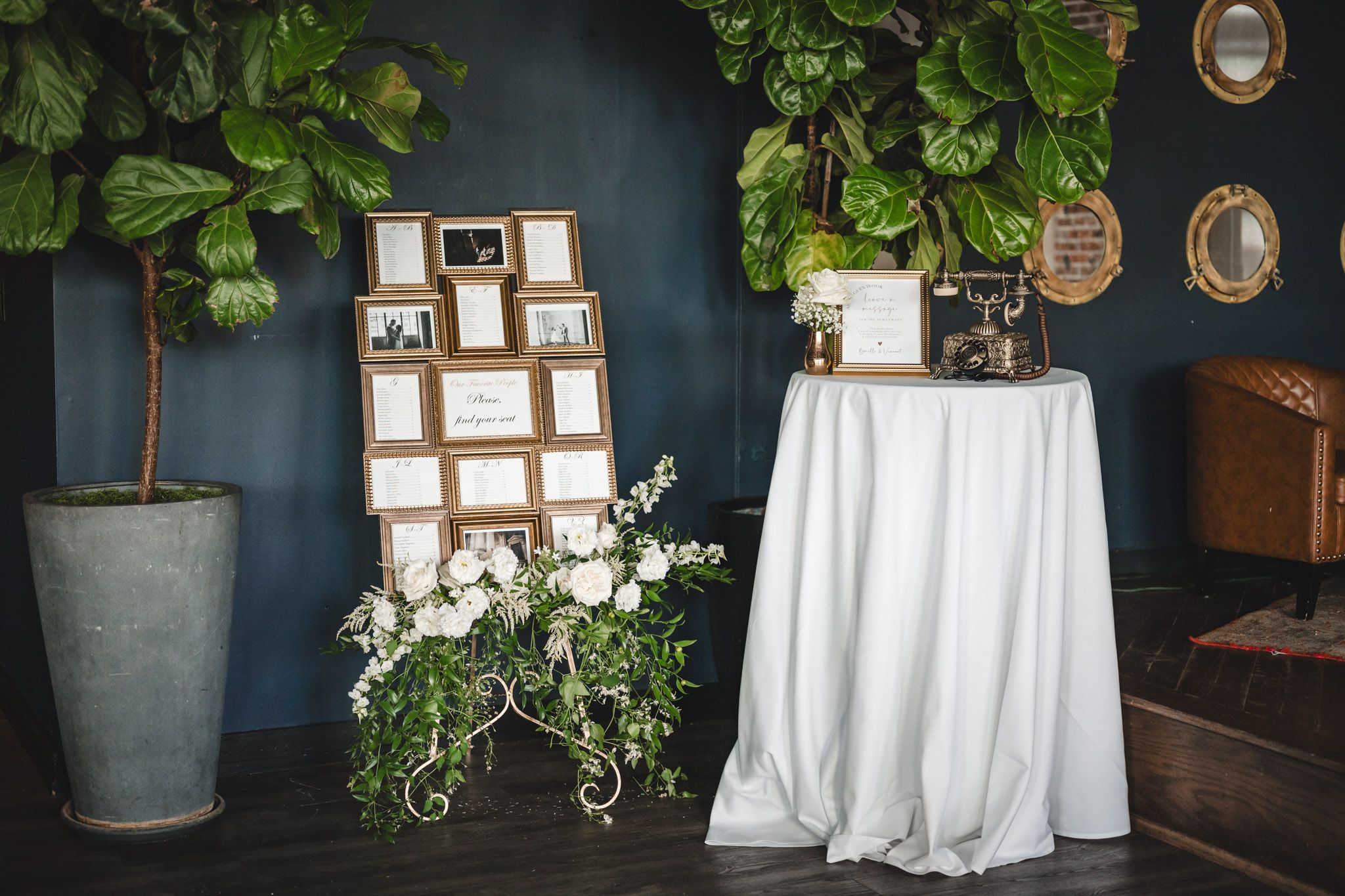 Dark blue wall decorated with vintage frames and lush green plants creating an elegant ambiance.