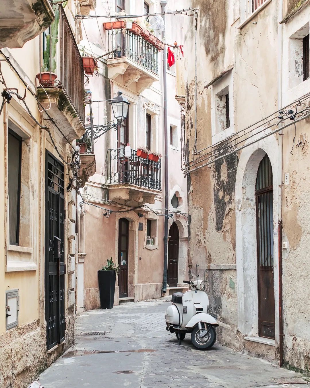 Quiet European alleyway with stone buildings and a parked scooter in soft daylight.