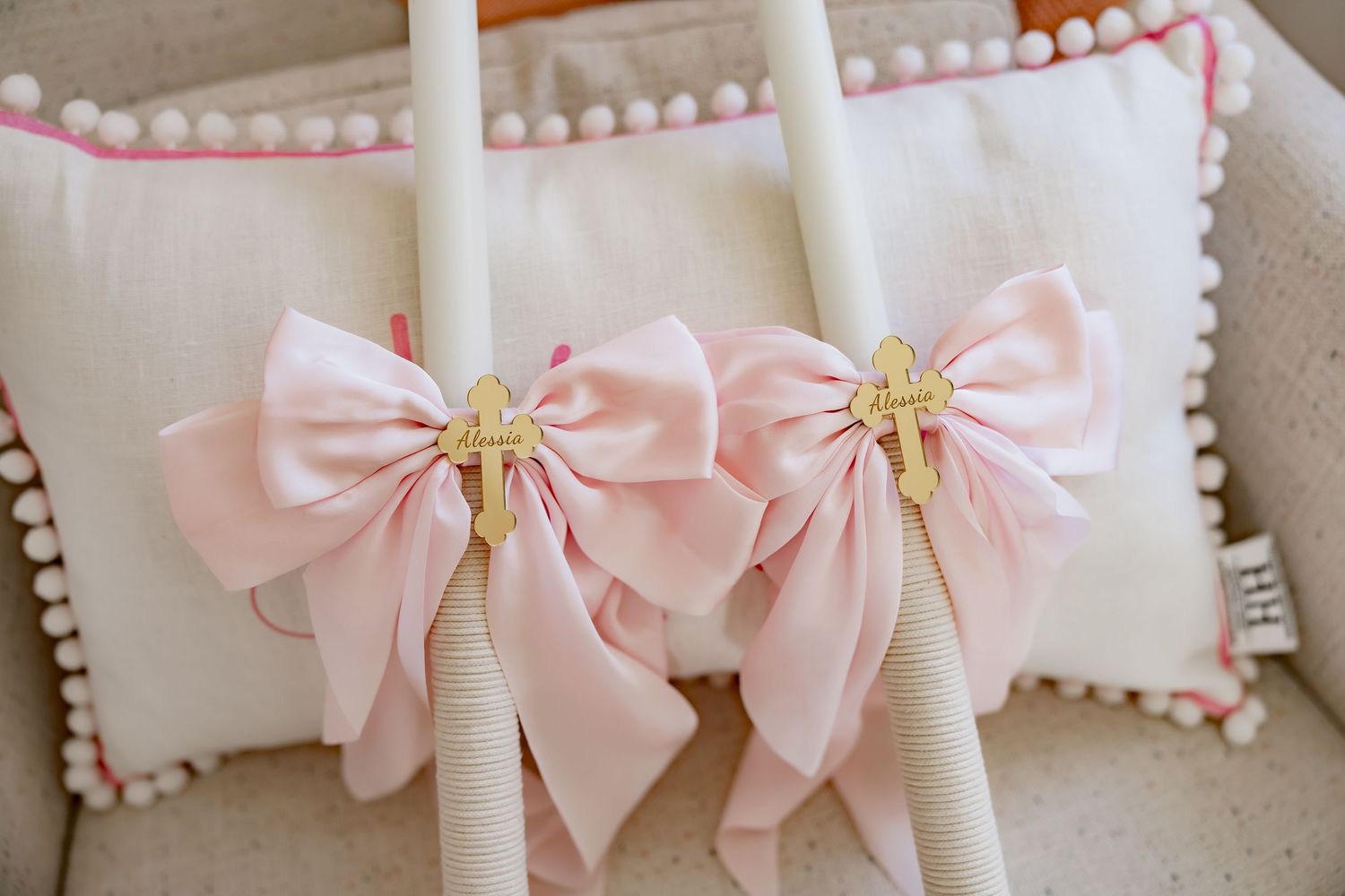 Pink satin bows with gold accents decorate white pillars in a delicate wedding display.