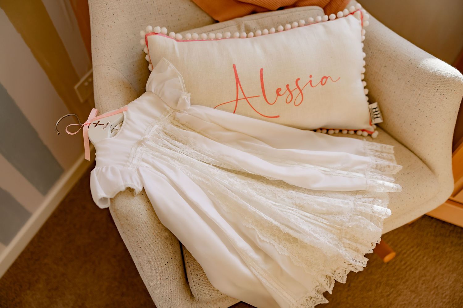 White wedding dress laid out on a beige chair with delicate details and embroidery.