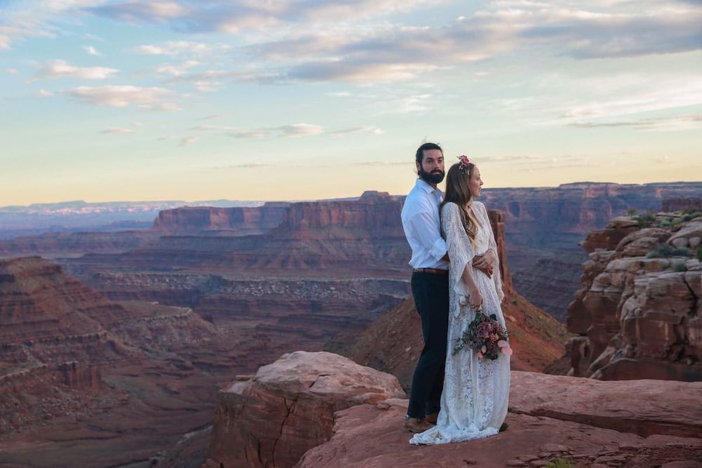 A couple poses for romantic sunset photos at Dead Horse Point State Park overlooking the dramatic canyon landscape.