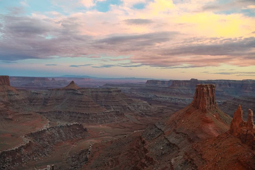 Panoramic sunset view over red rock canyons and mesas in Canyonlands National Park, Utah, with dramatic cloudy skies.