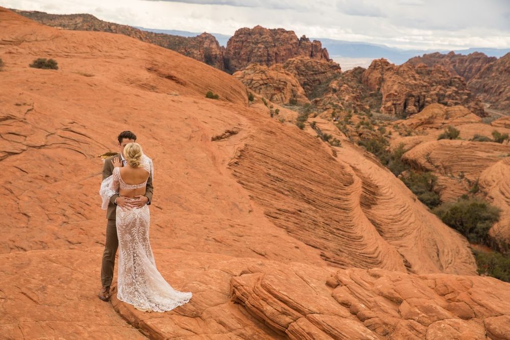 A couple in wedding attire embraces among the dramatic red rock formations of Valley of Fire State Park in Nevada.